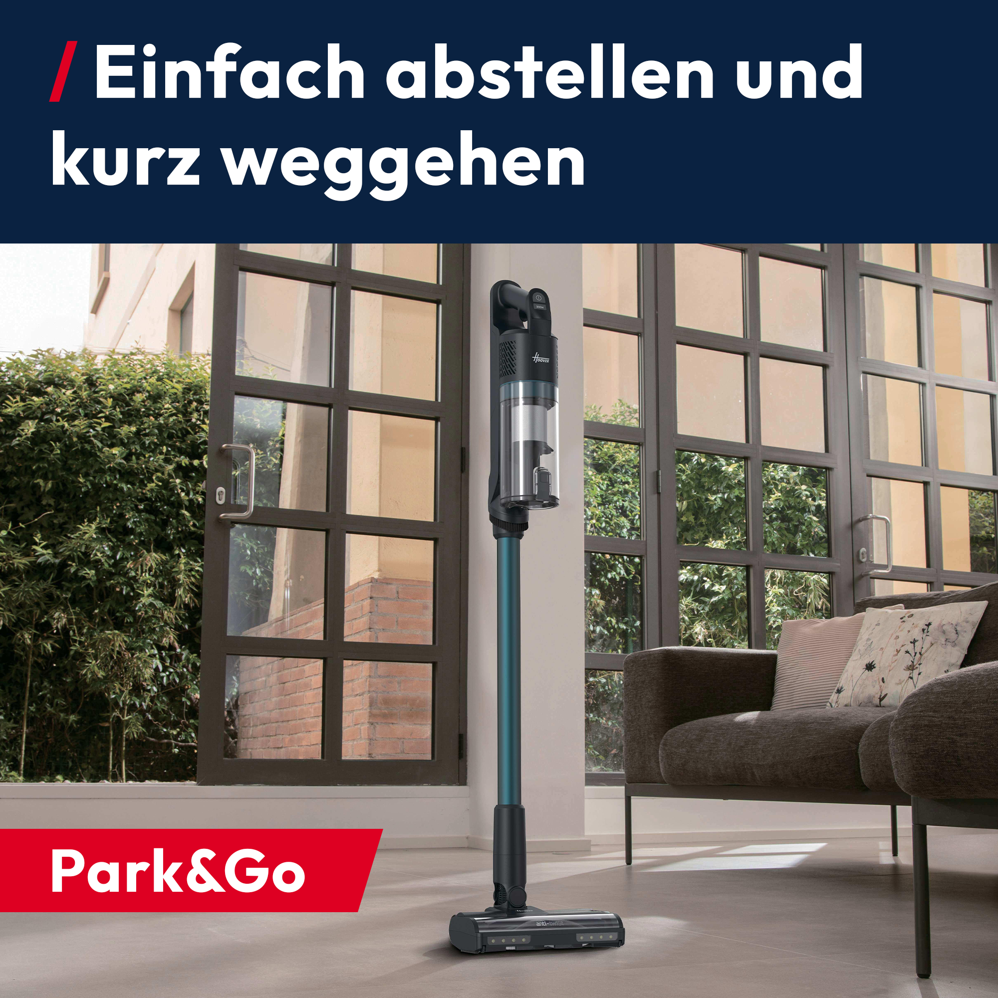 Ein blauer Staubsauger steht in einem Wohnzimmer neben einer Glasfront.