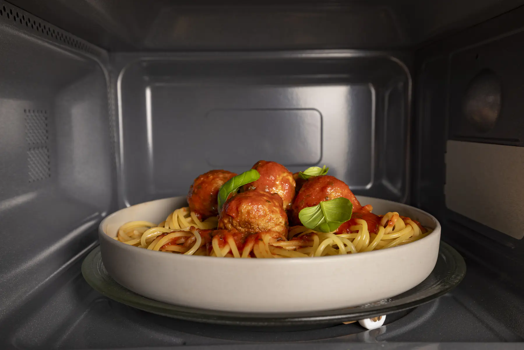 Spaghetti z klopsikami w sosie pomidorowym w misce w kuchence mikrofalowej.