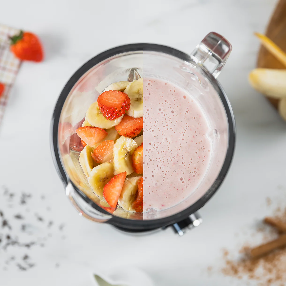 Una licuadora con mitad fresas y plátanos, mitad batido de fresa y plátano.