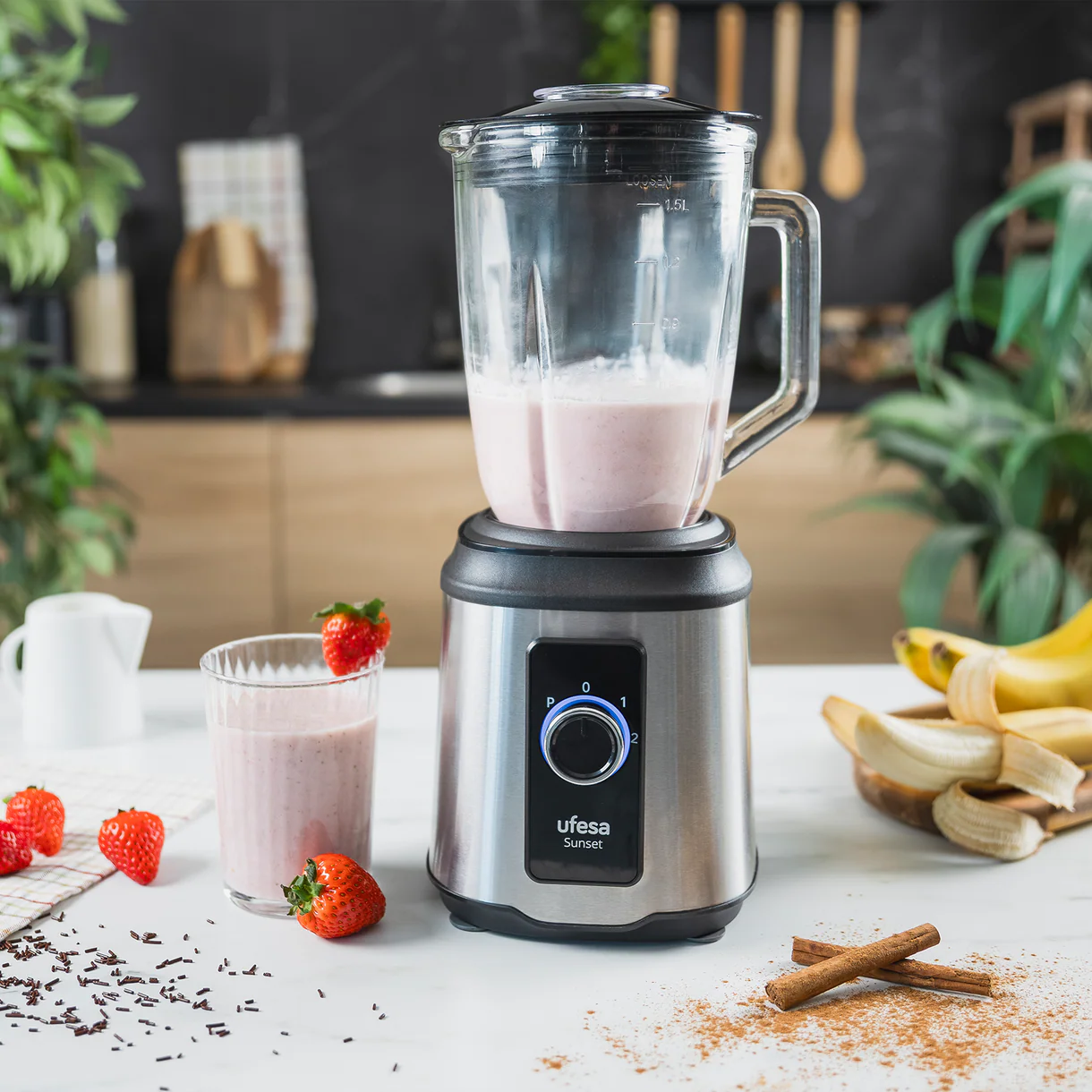 Una licuadora con batido de fresa e ingredientes.