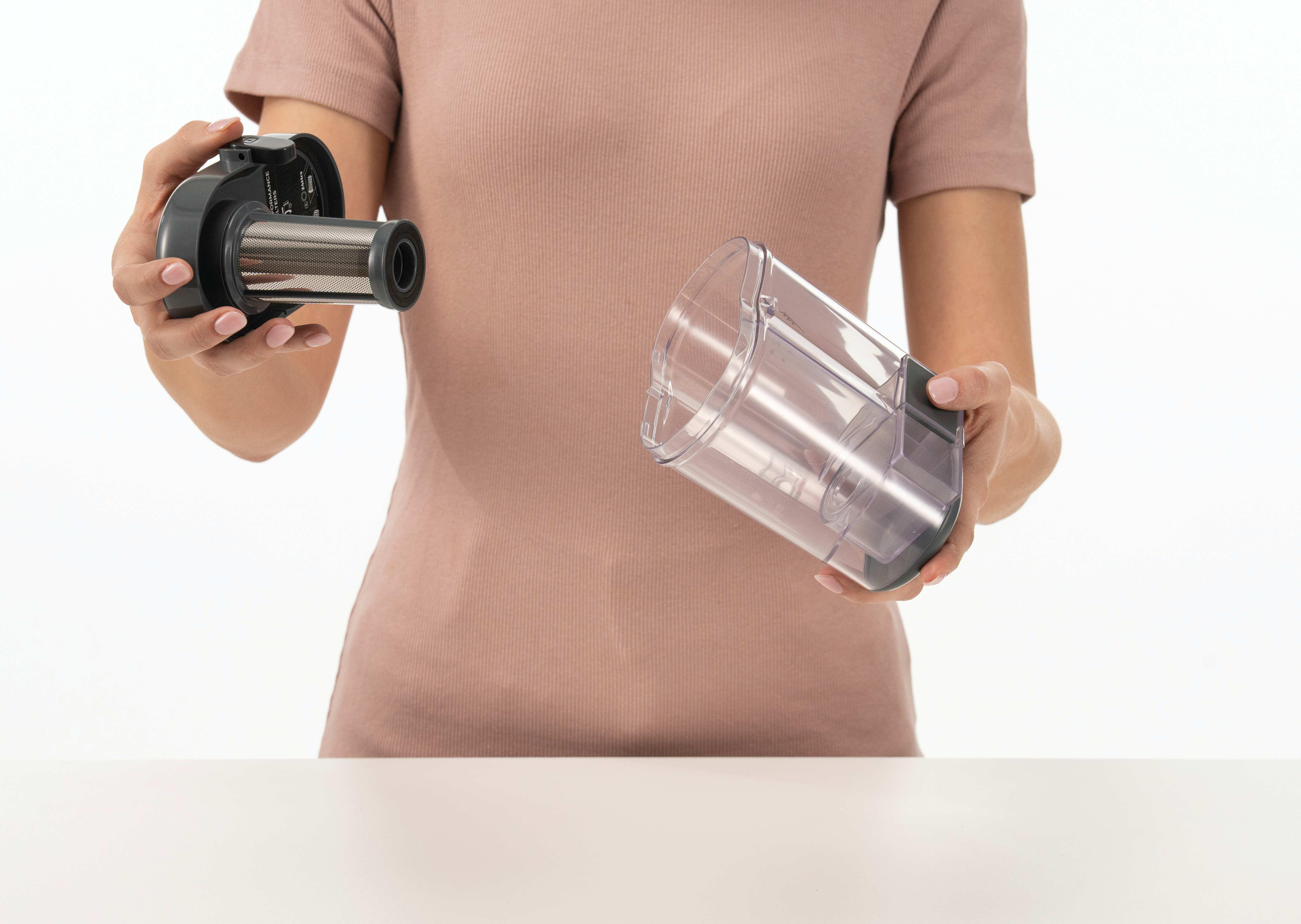 Eine Person hält einen Staubbehälter und einen Filter eines Staubsaugers.