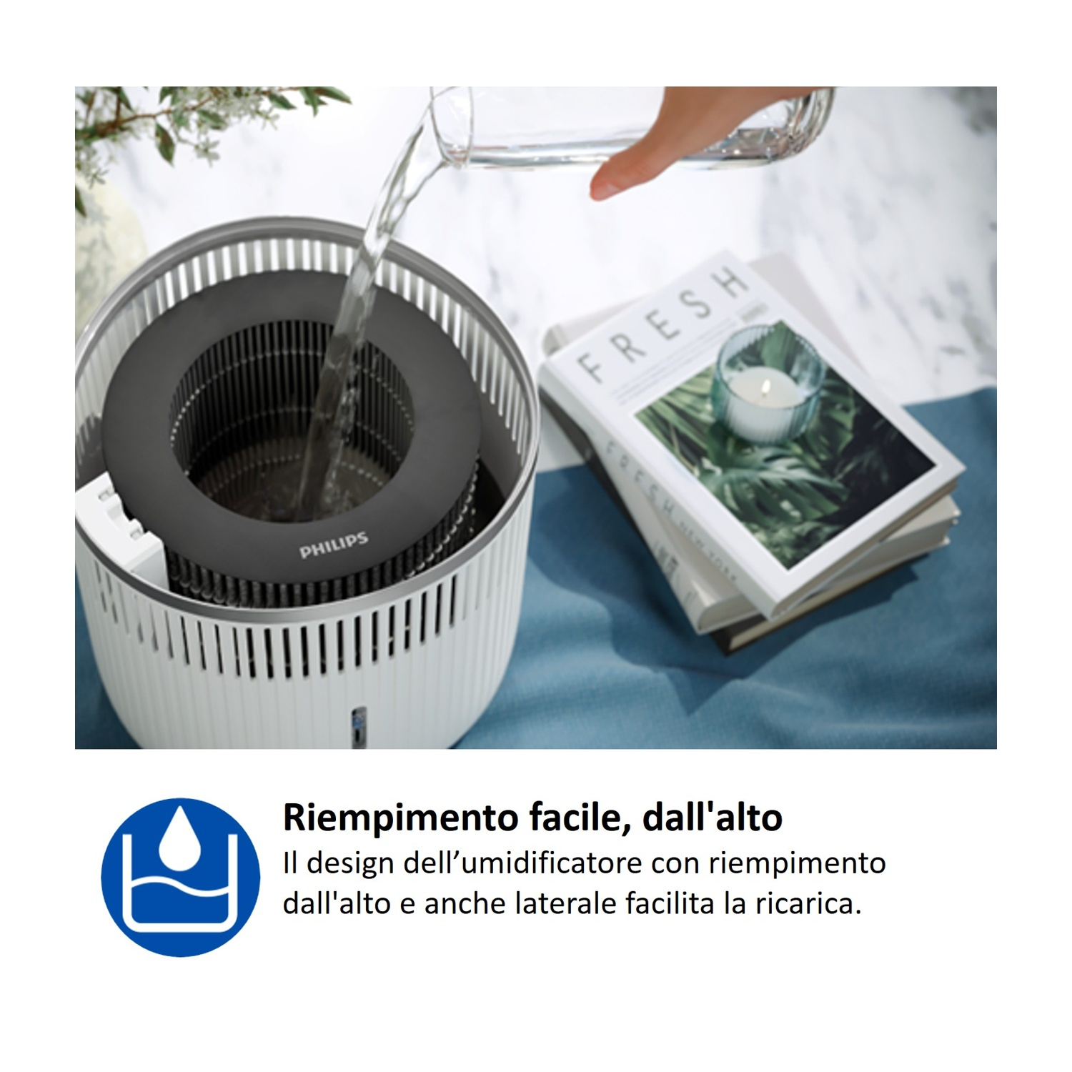 Acqua versata in un umidificatore Philips bianco, accanto a libri.
