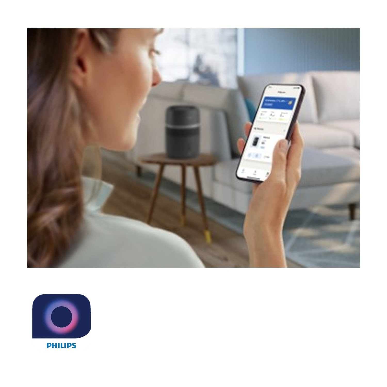 Donna usa app Philips su smartphone vicino a speaker in soggiorno.