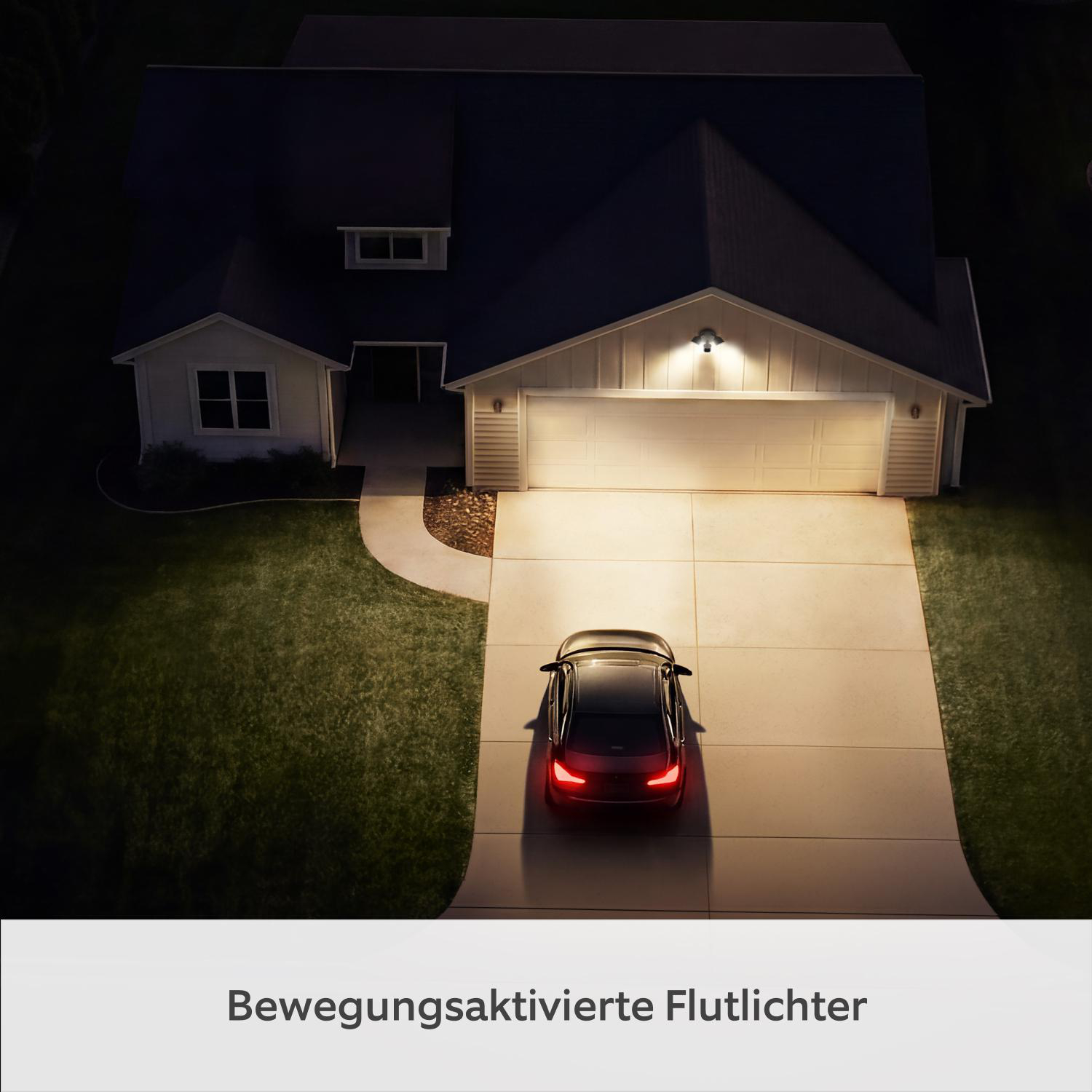 Ein schwarzes Auto parkt nachts auf einer Auffahrt vor einem Haus mit Garagentor.