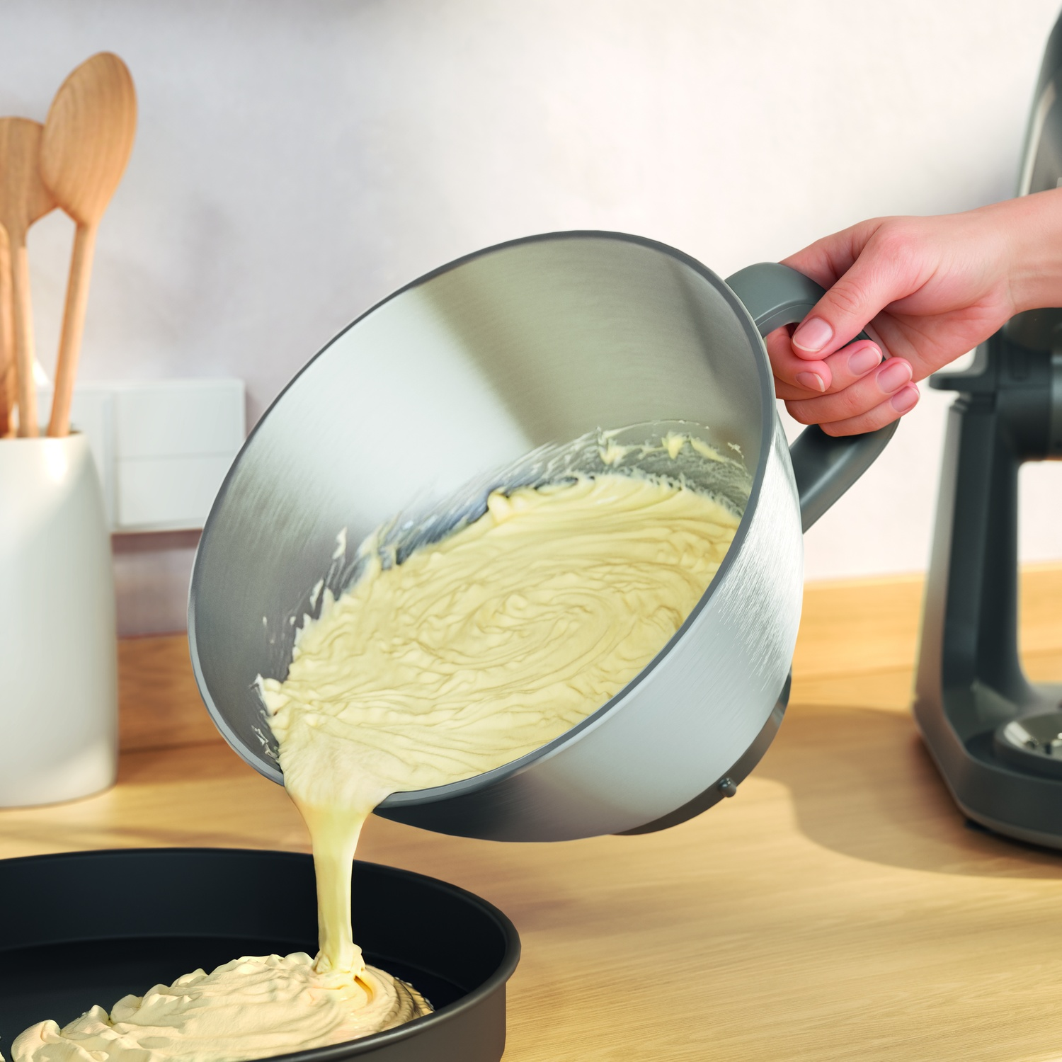 A batter is poured from a bowl into a baking pan.