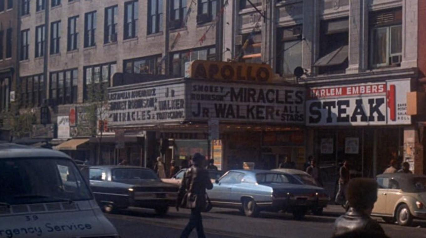Apollo Theater mit Leuchtreklame; Autos und Fußgänger auf der Straße.