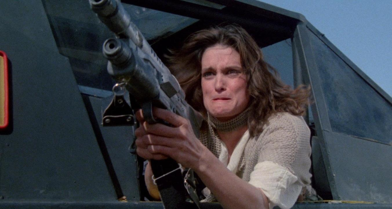 Frau mit Waffe in einem Fahrzeug vor blauem Himmel