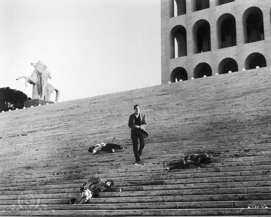 Ein Mann geht eine große Steintreppe hinauf, wo mehrere Personen liegen.