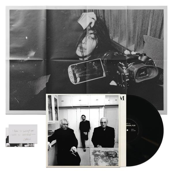 Schwarz-Weiß-Foto: gefaltetes Poster mit Frau & Camcorder, LP und Foto von drei Männern.