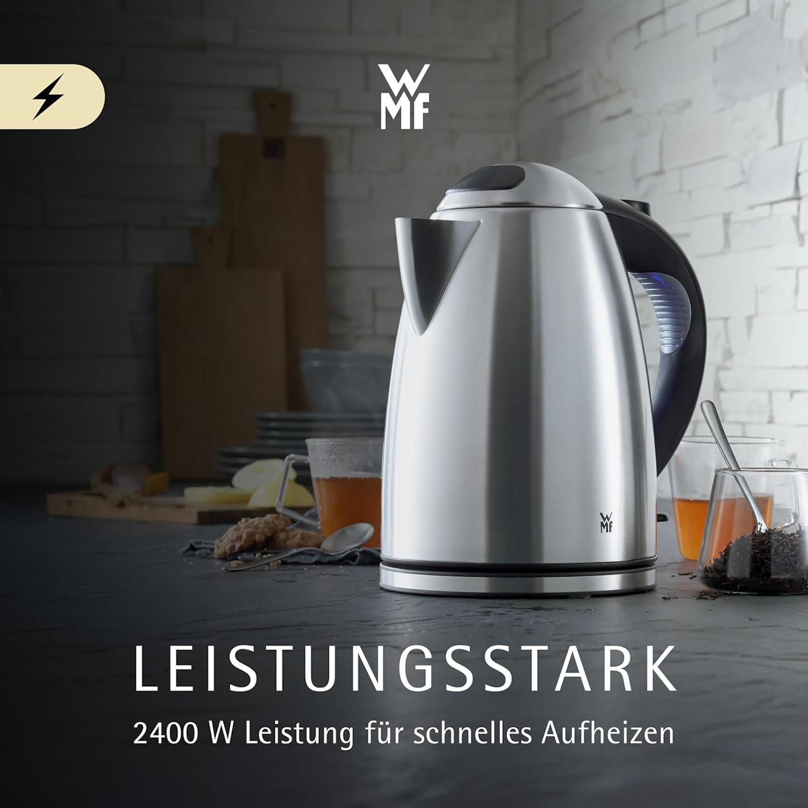 Ein silberner Wasserkocher steht auf einem Tisch mit Tee und Keksen.