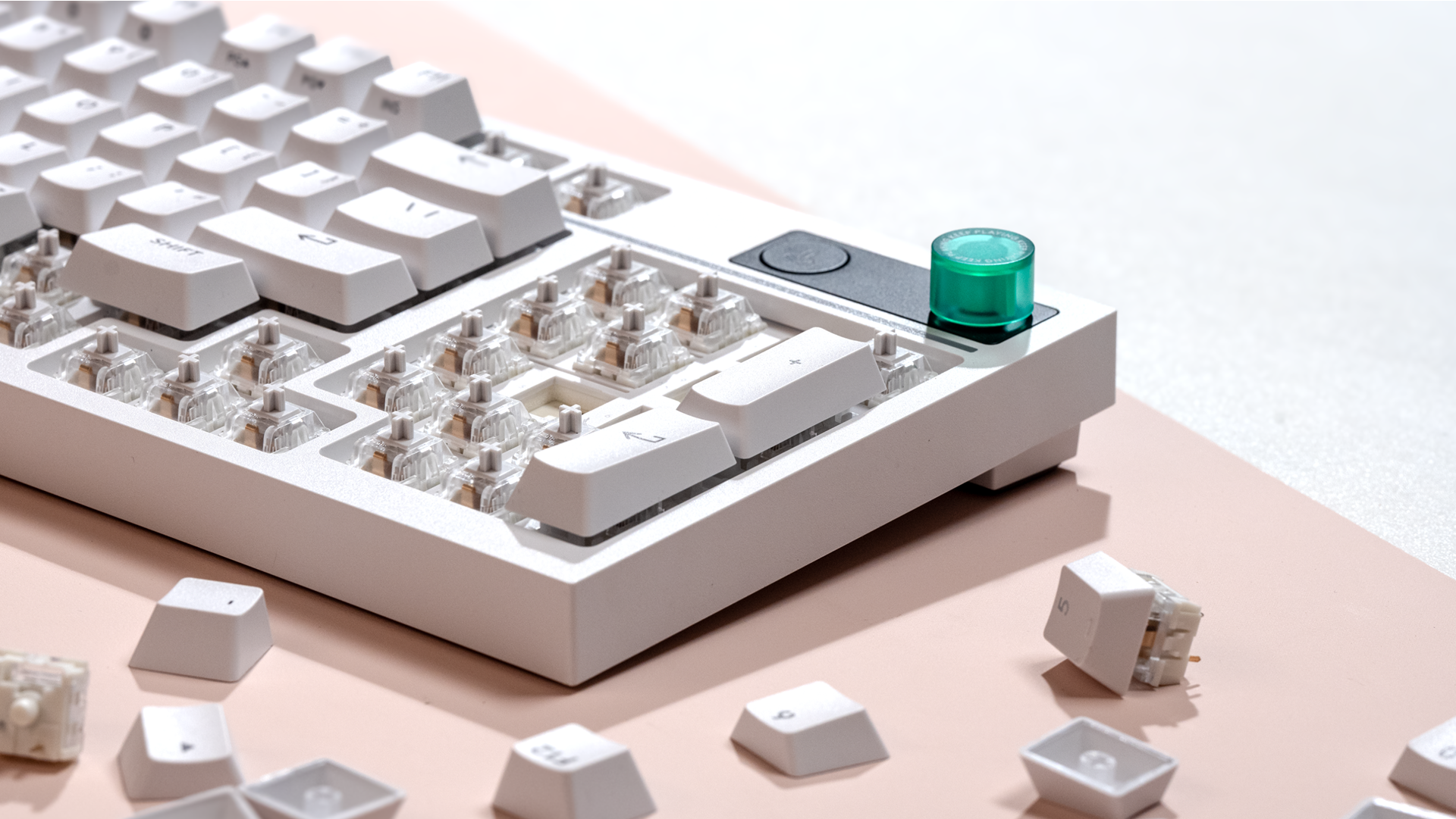 Primer plano de un teclado mecánico blanco sin teclas, mostrando interruptores y un dial verde.