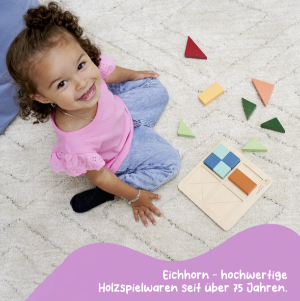 Ein kleines Mädchen spielt mit bunten Holzbausteinen auf einem Teppich.