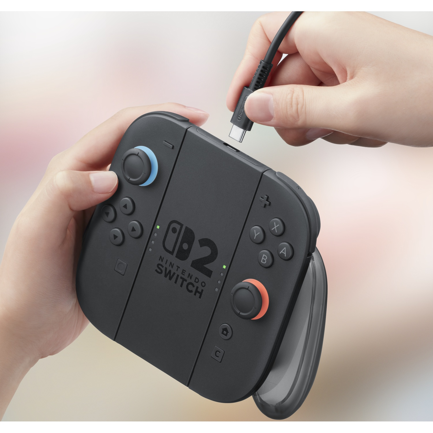 Een hand sluit een USB-C kabel aan op een zwarte Nintendo Switch controller.