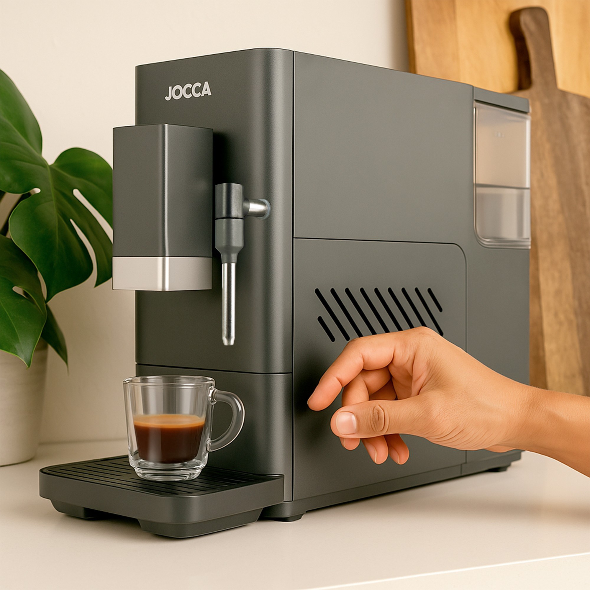 Una cafetera gris JOCCA con una taza de espresso y una mano presionando un botón.