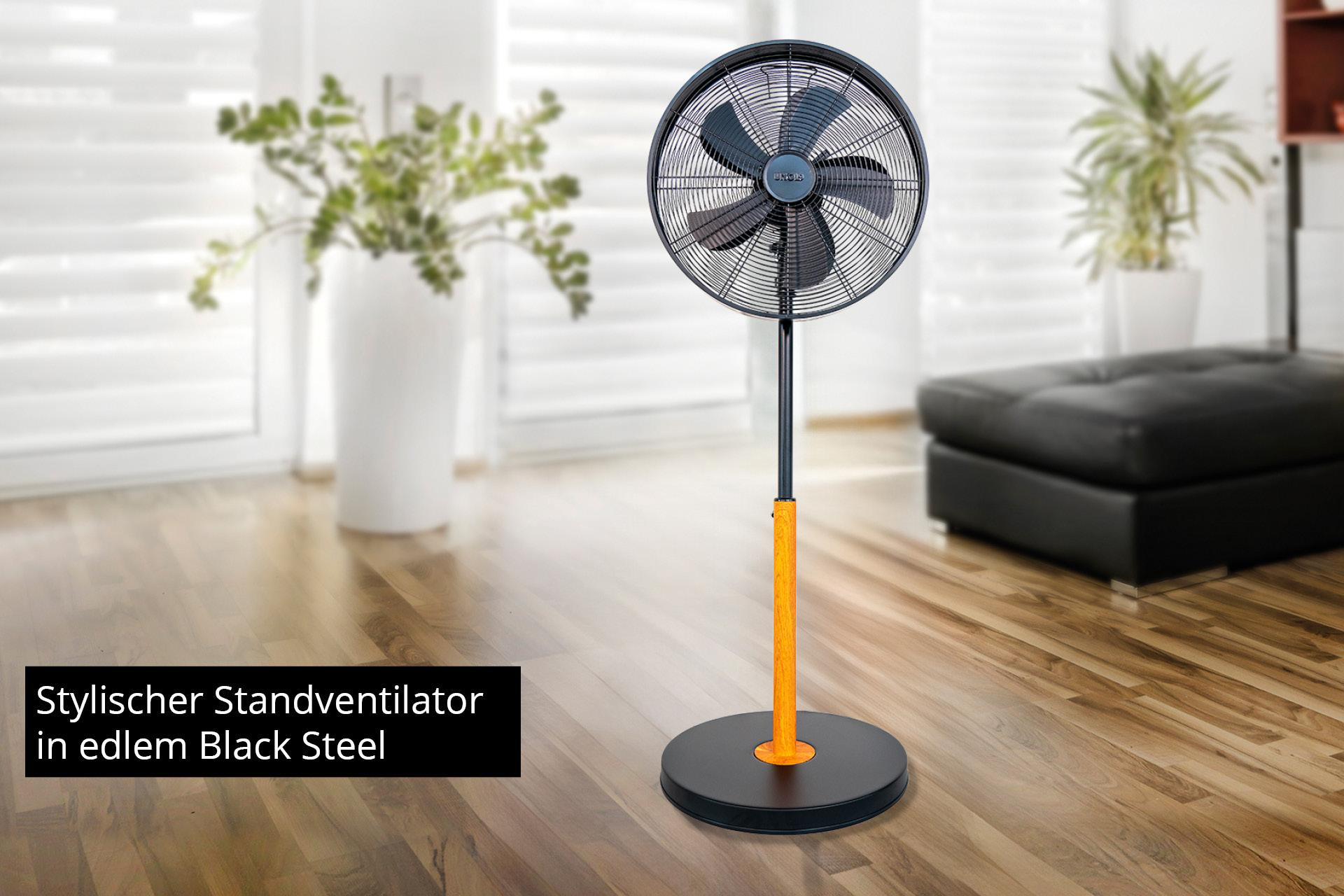 Ein schwarzer Standventilator mit orangefarbenem Ständer auf einem Holzboden.