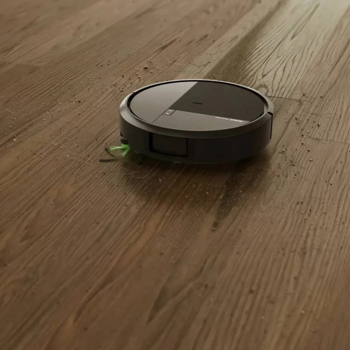 Okrągły czarny robot sprzątający czyści drewnianą podłogę.