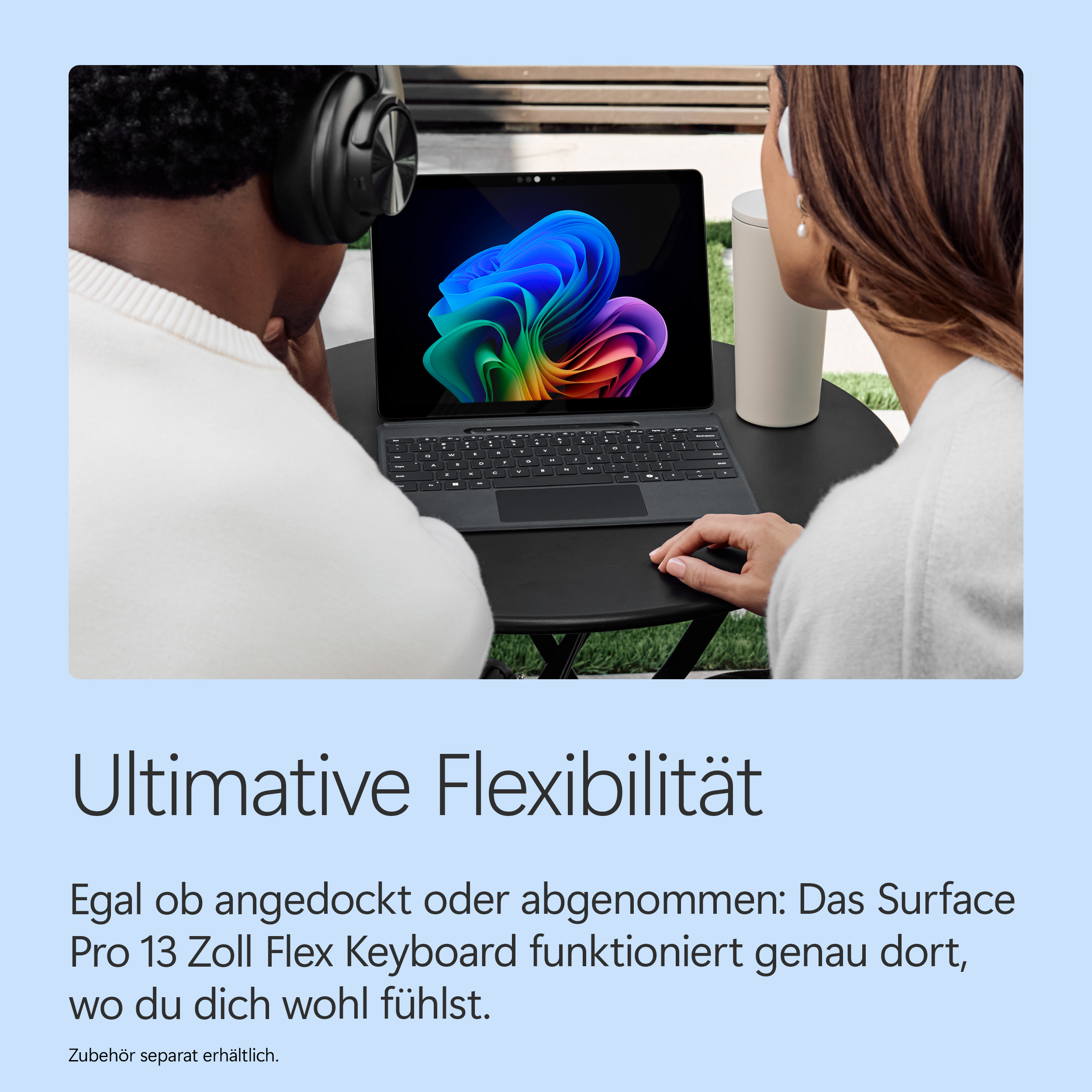 Zwei Personen mit Kopfhörern sitzen an einem Tisch und nutzen ein Surface Pro mit Tastatur.