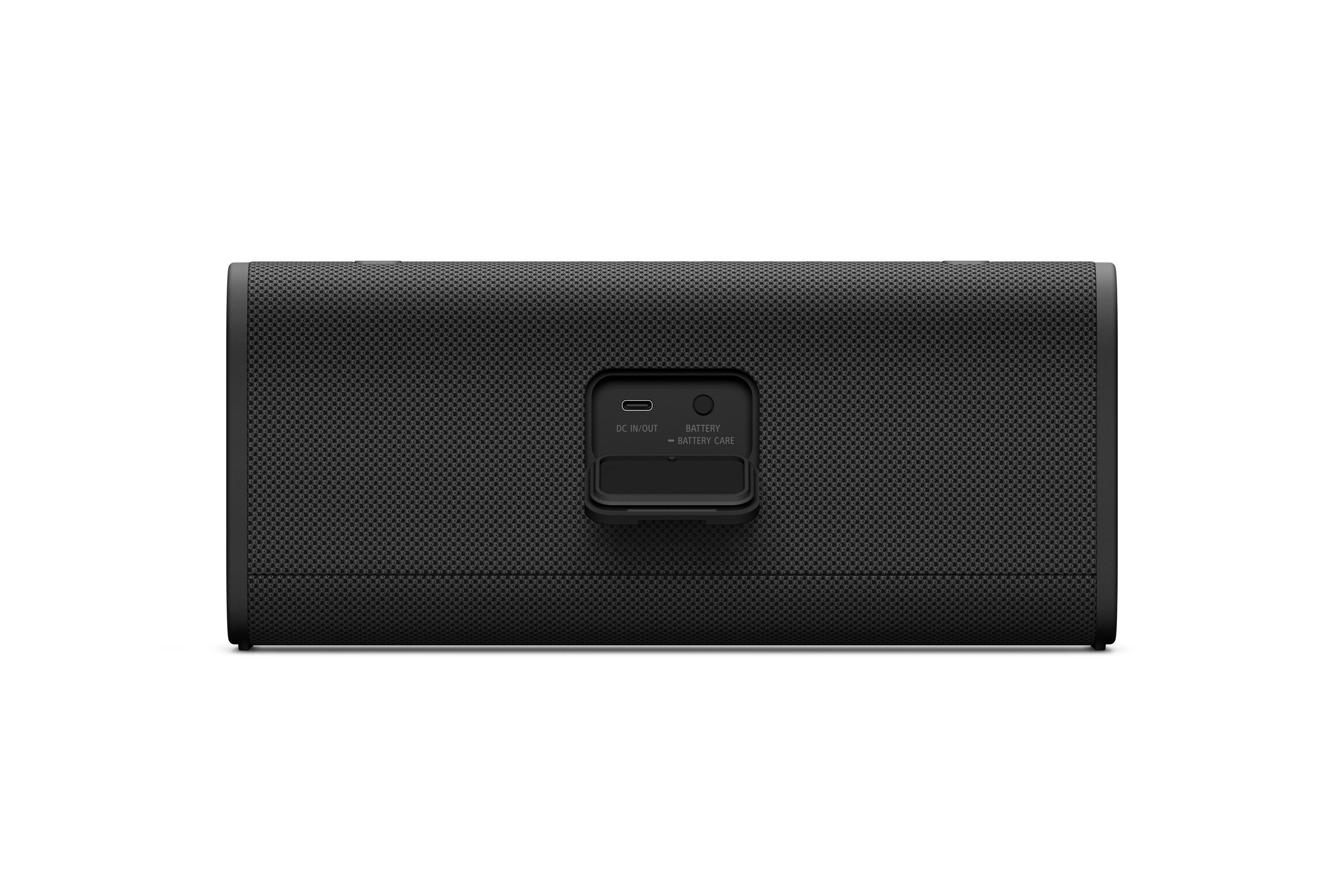 Altavoz negro con tapa abierta mostrando puertos DC IN/OUT y BATTERY.