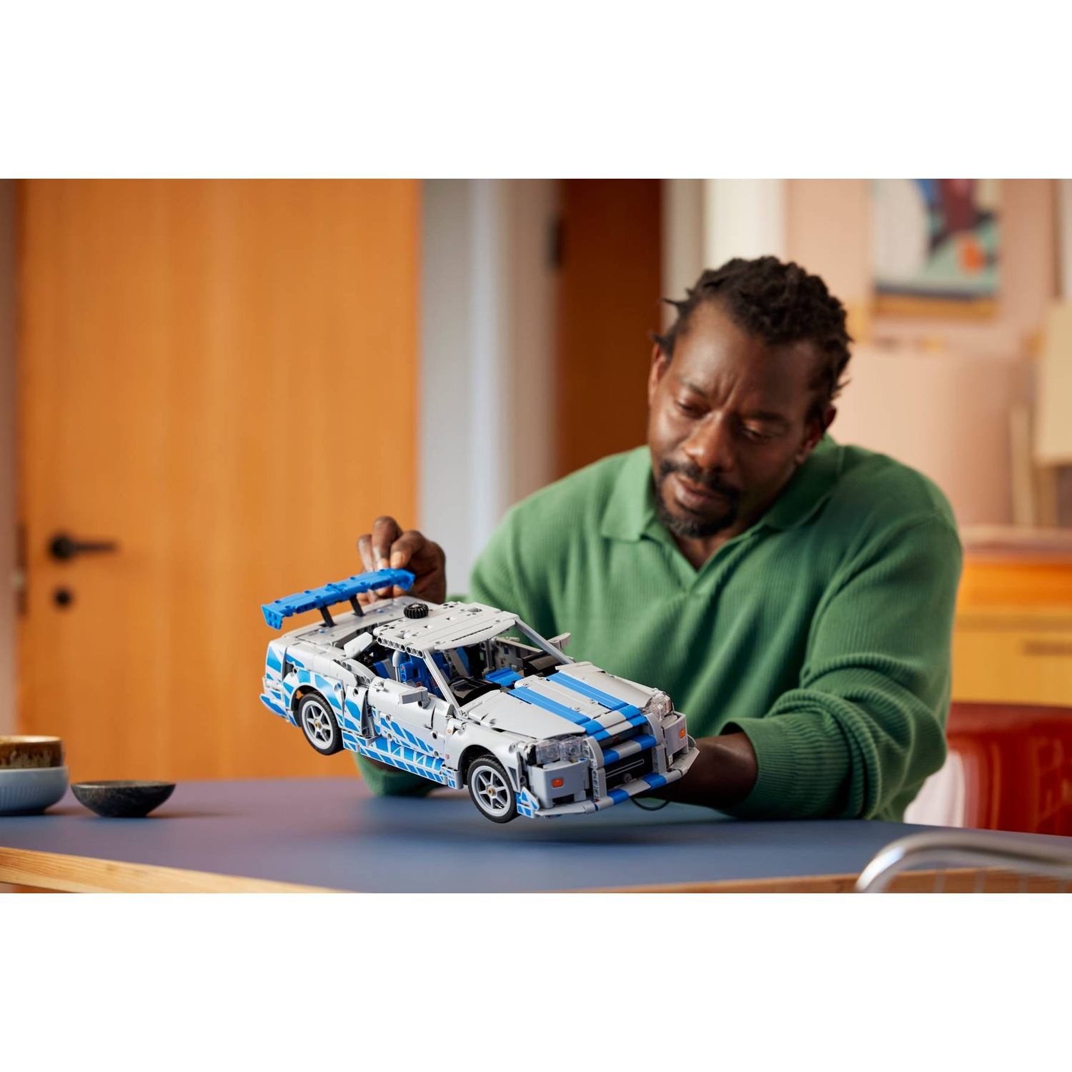 Un uomo tiene un'auto Lego bianca e blu con ali.