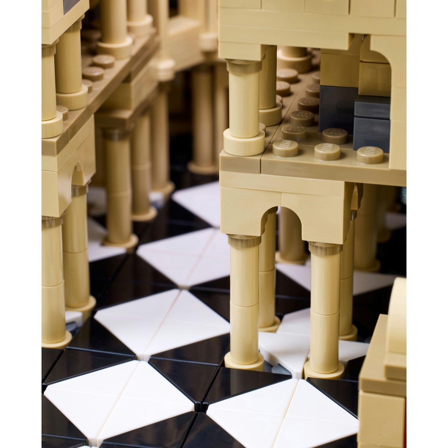 Un modello Lego di un edificio con colonne e un pavimento bianco e nero.