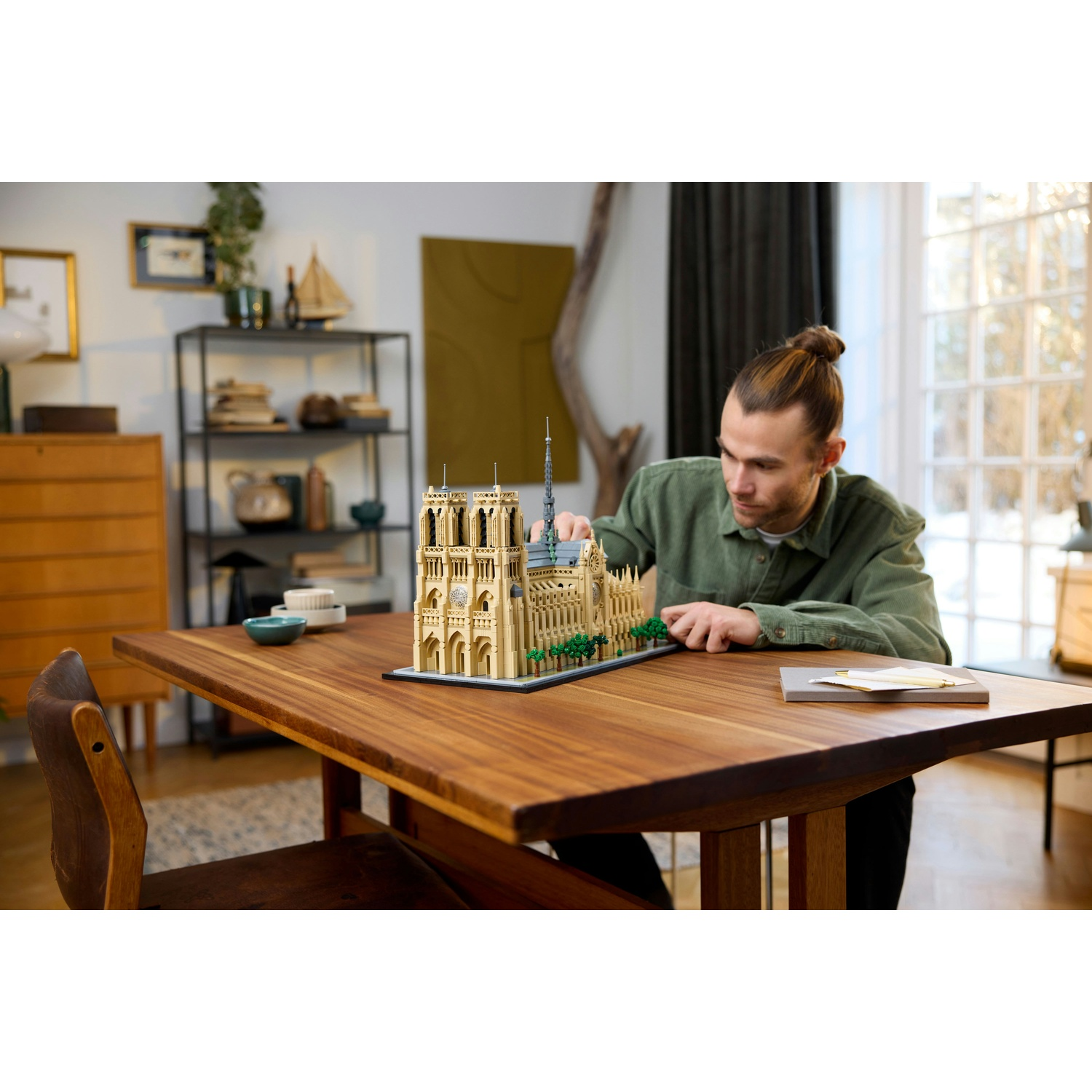 Uomo costruisce dettagliato modello Lego di Notre Dame su tavolo legno.
