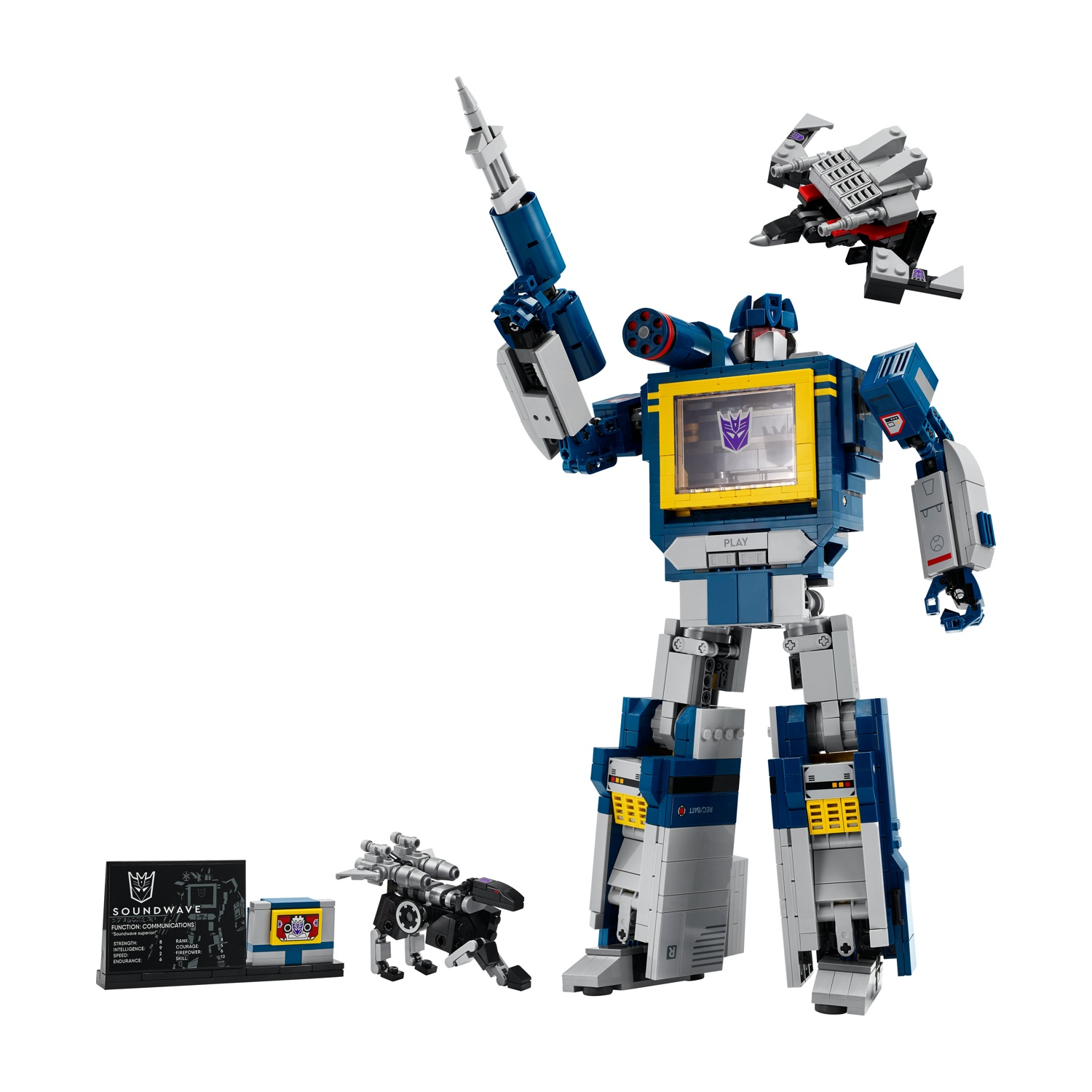 Un Transformer blu e grigio si erge con una pistola laser, accanto a un piccolo robot e una cassetta.