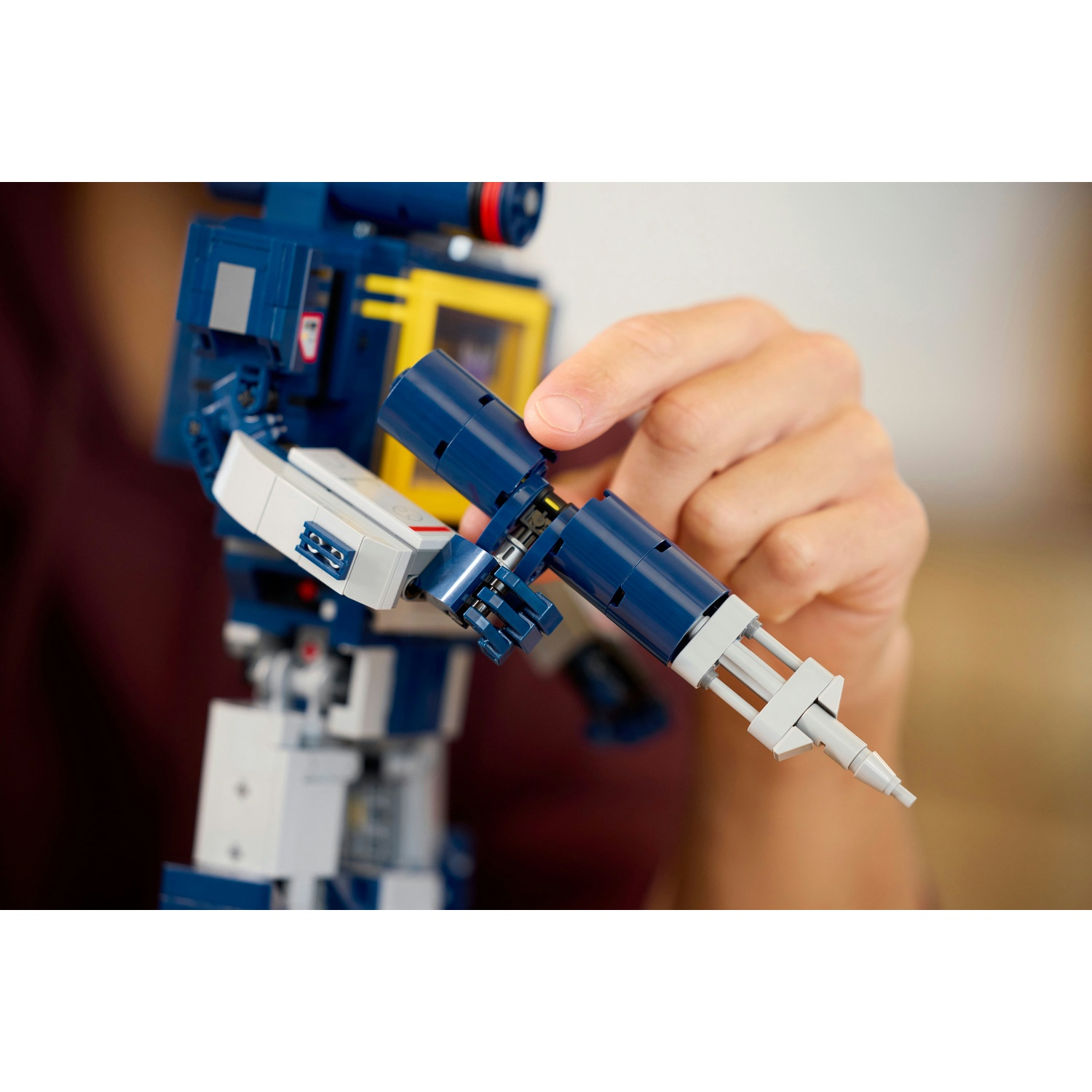 Una mano tiene un giocattolo robot blu e grigio con una pistola.