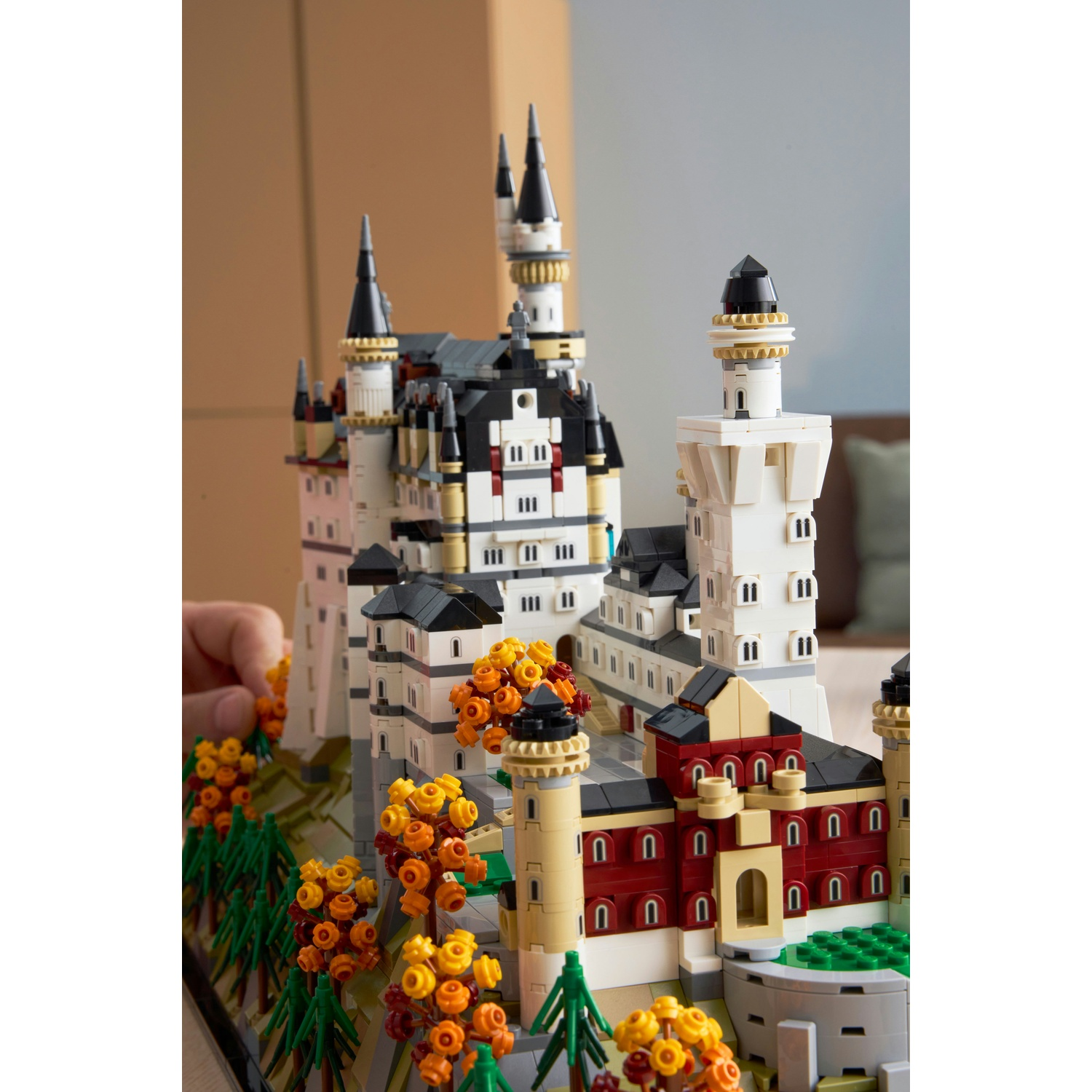 Un dettagliato modello di castello Lego con torri, accenti rossi e fogliame autunnale.
