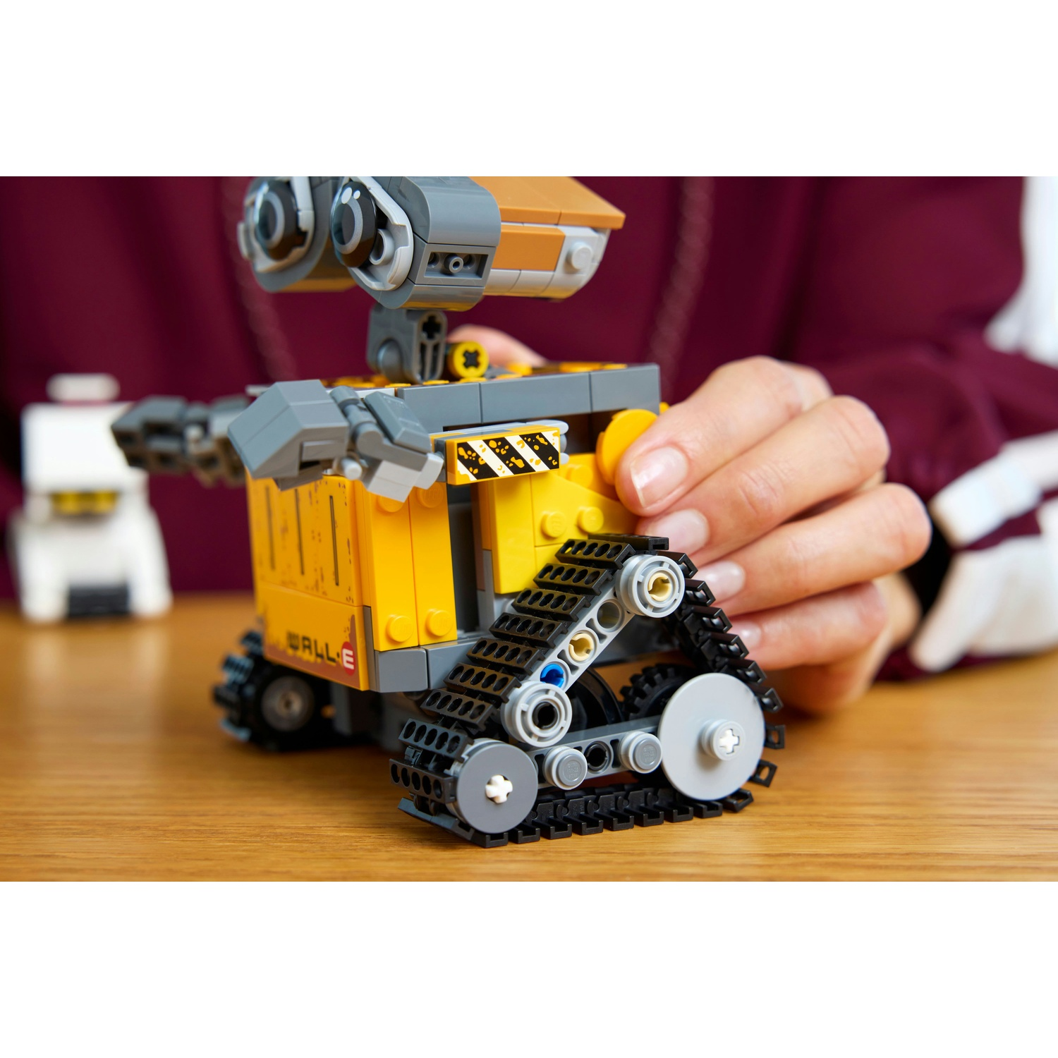 Un robot Lego giallo con cingoli è su un tavolo di legno.
