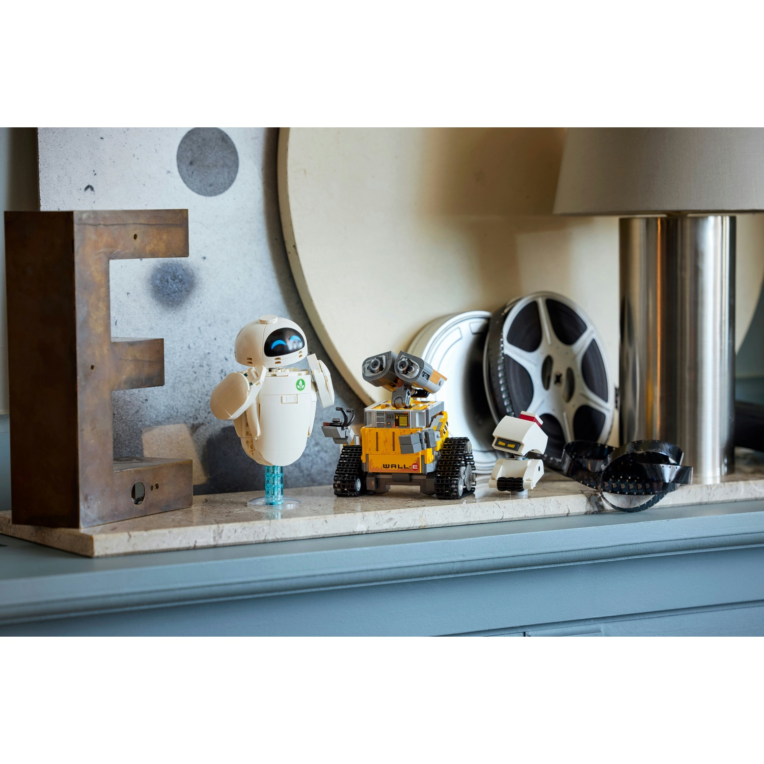 Tre figure di robot, tra cui WALL-E, su uno scaffale accanto a una grande lettera E.