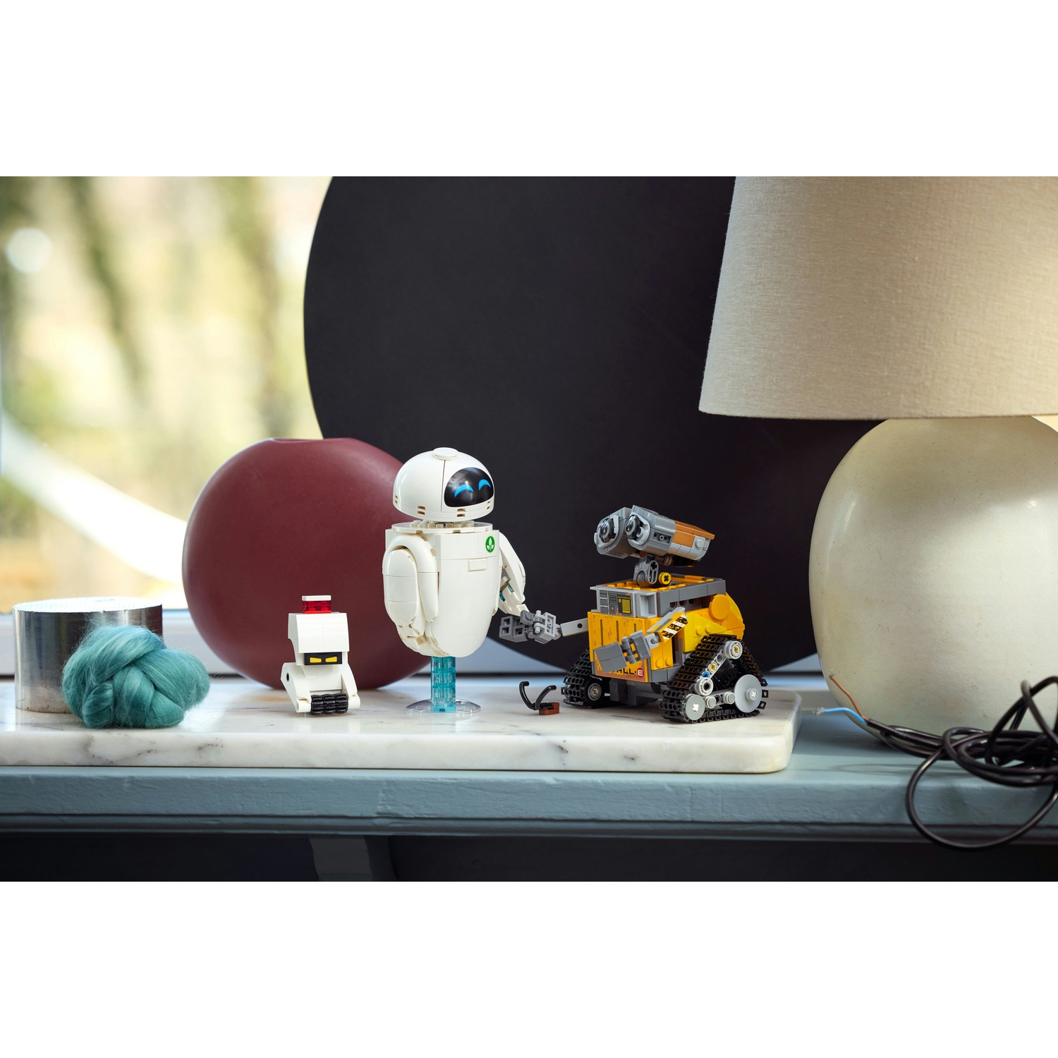Tre figure robotiche su una base di marmo. Un piccolo robot bianco a sinistra, EVE accanto, WALL-E a destra.