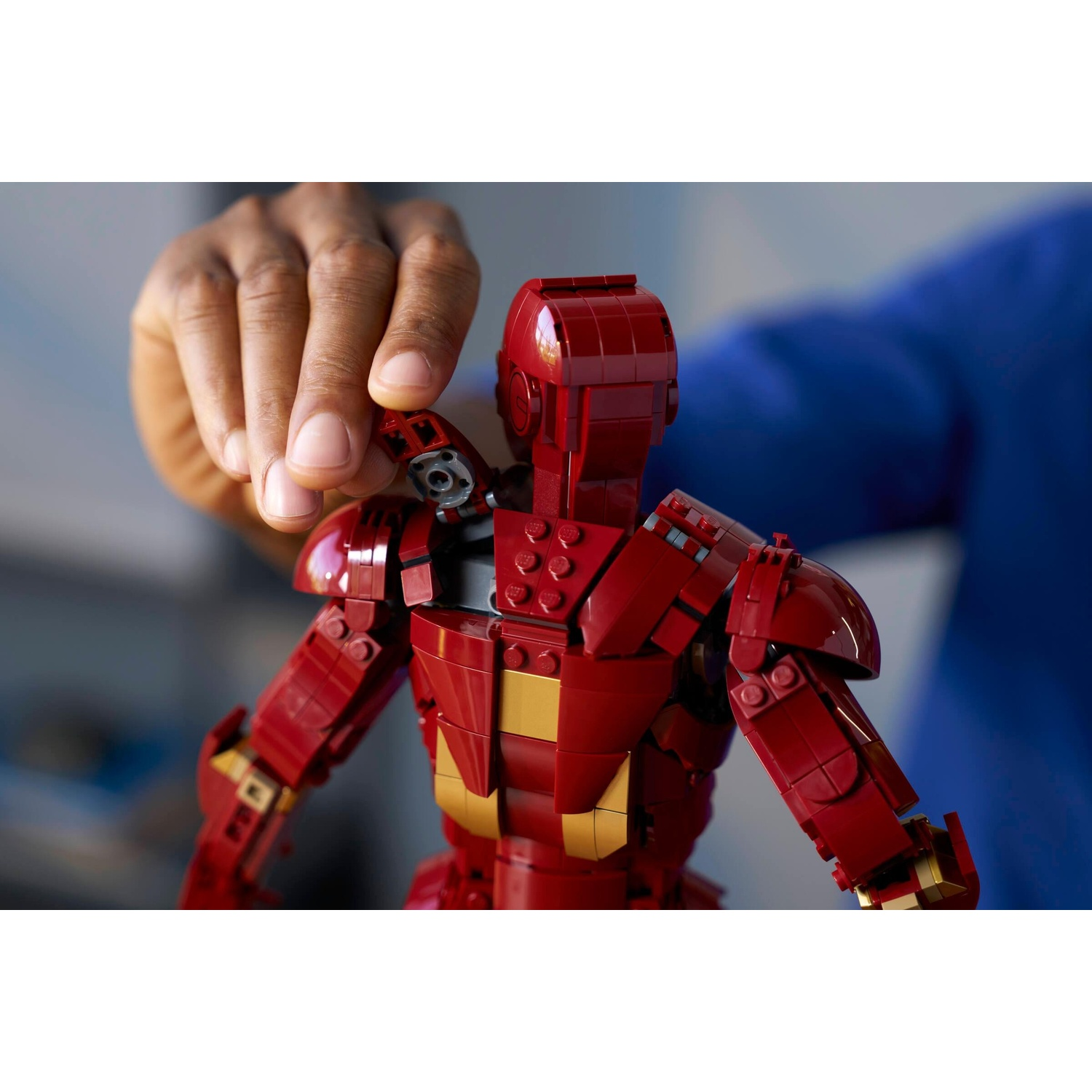 Una mano tiene una tuta Lego di Iron Man rossa con accenti dorati.