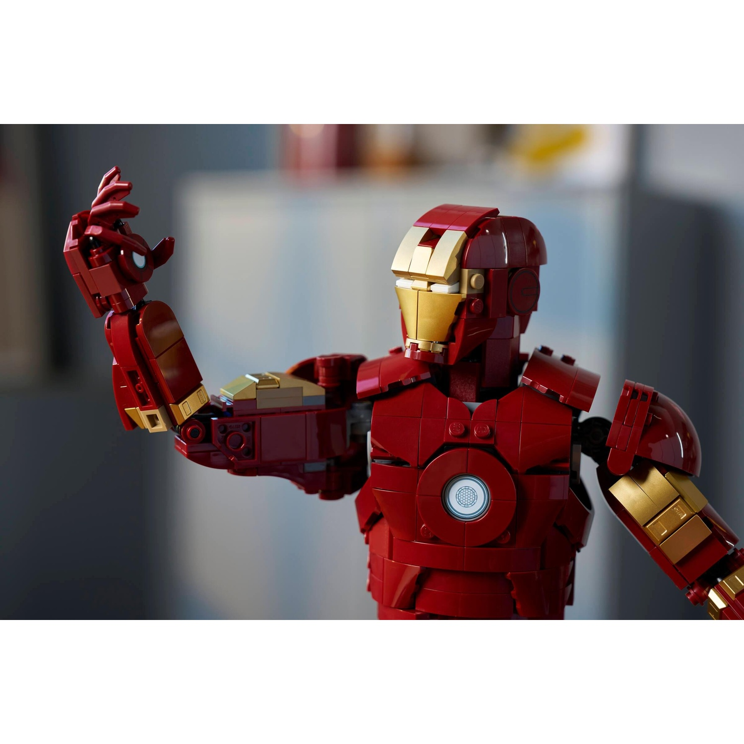 Figura Lego Iron Man rossa e oro con mano alzata su sfondo sfocato.