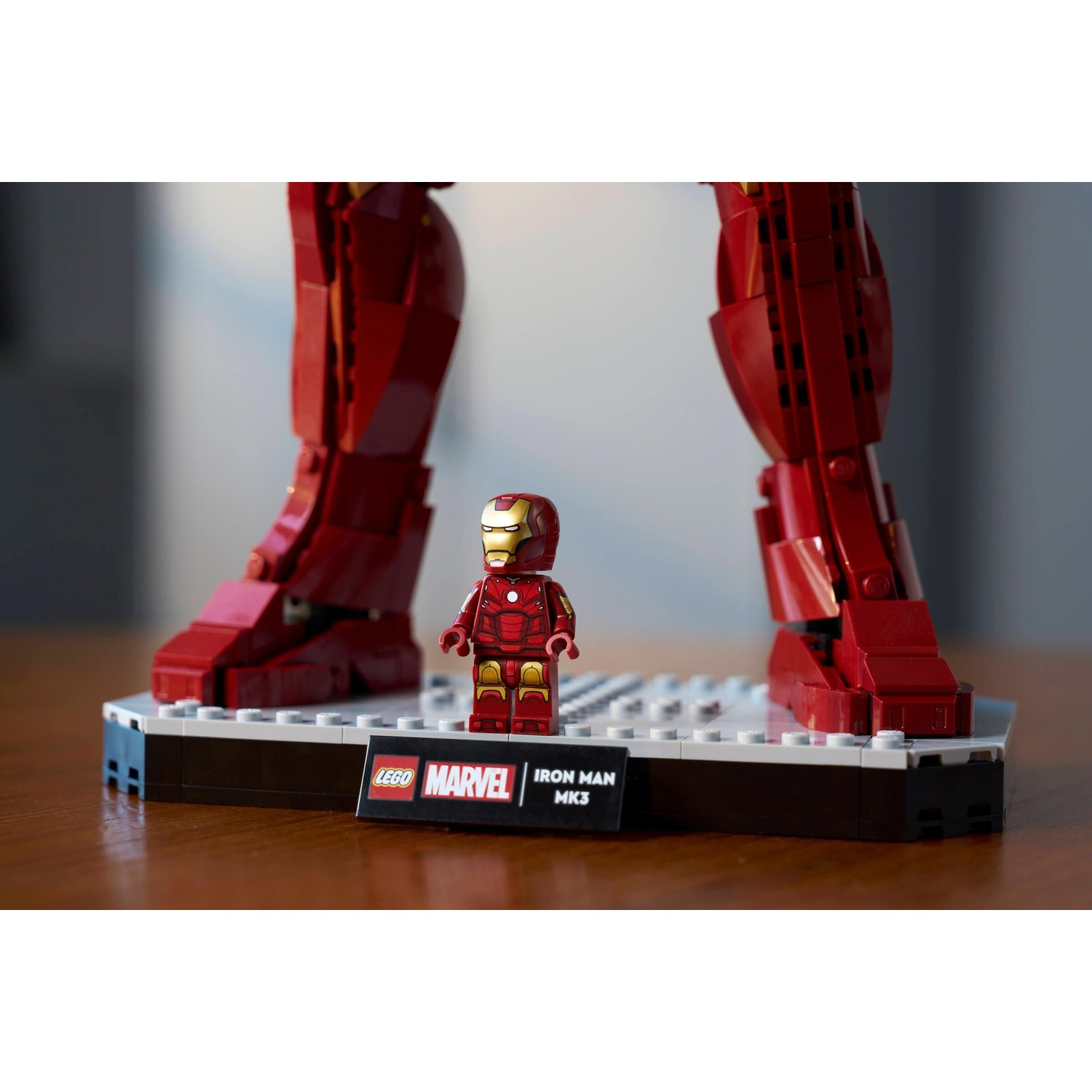 Figura Lego Iron Man Mk3 di fronte alle sue giganti gambe Lego rosse su una base.