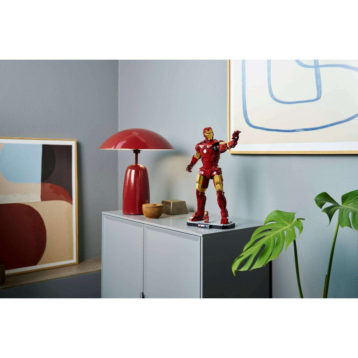 Statua di Iron Man su un mobile con lampada, arte e pianta.