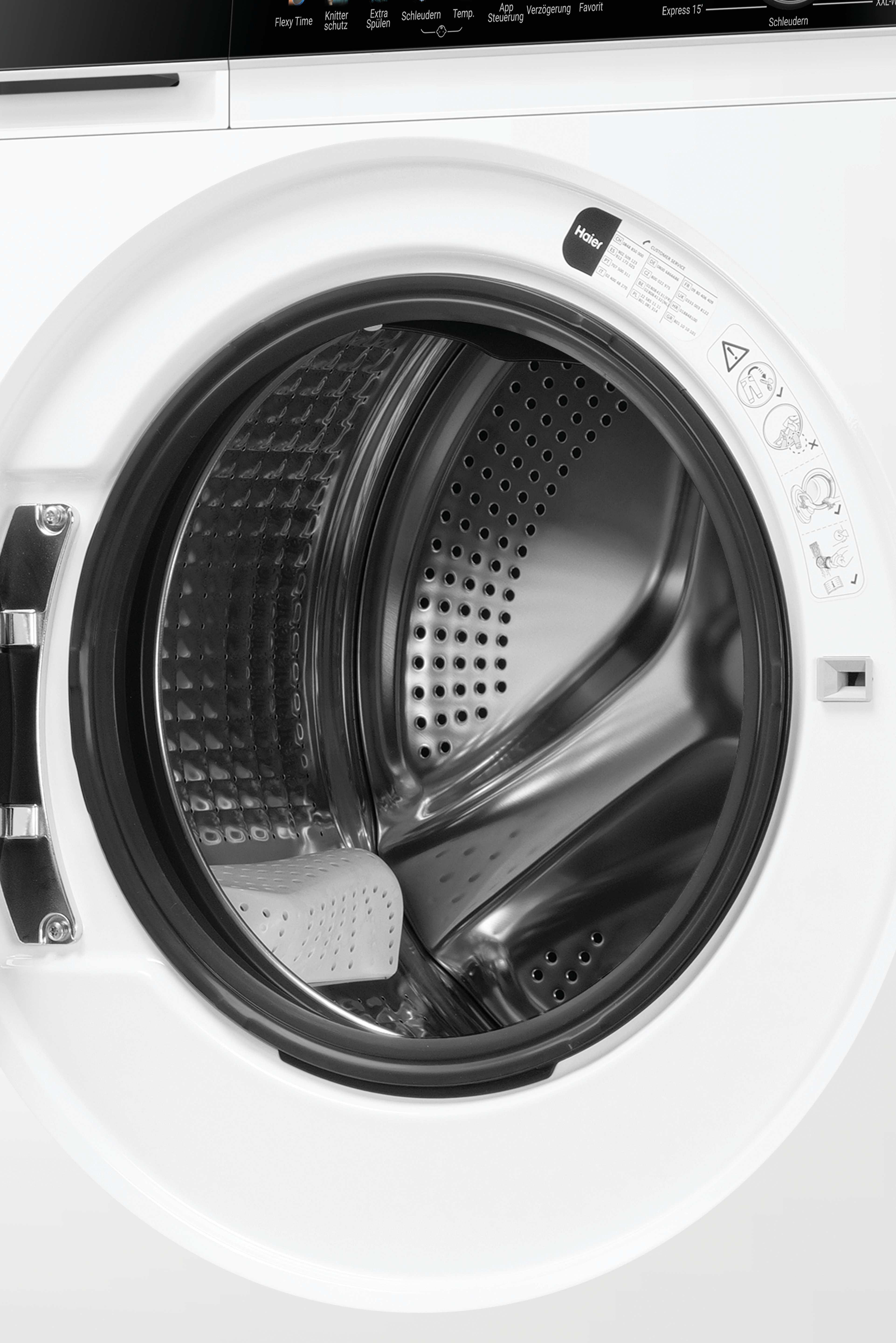 Eine weiße Waschmaschine mit geöffneter Trommel, die Hohlräume und ein kleines weißes Objekt zeigt.