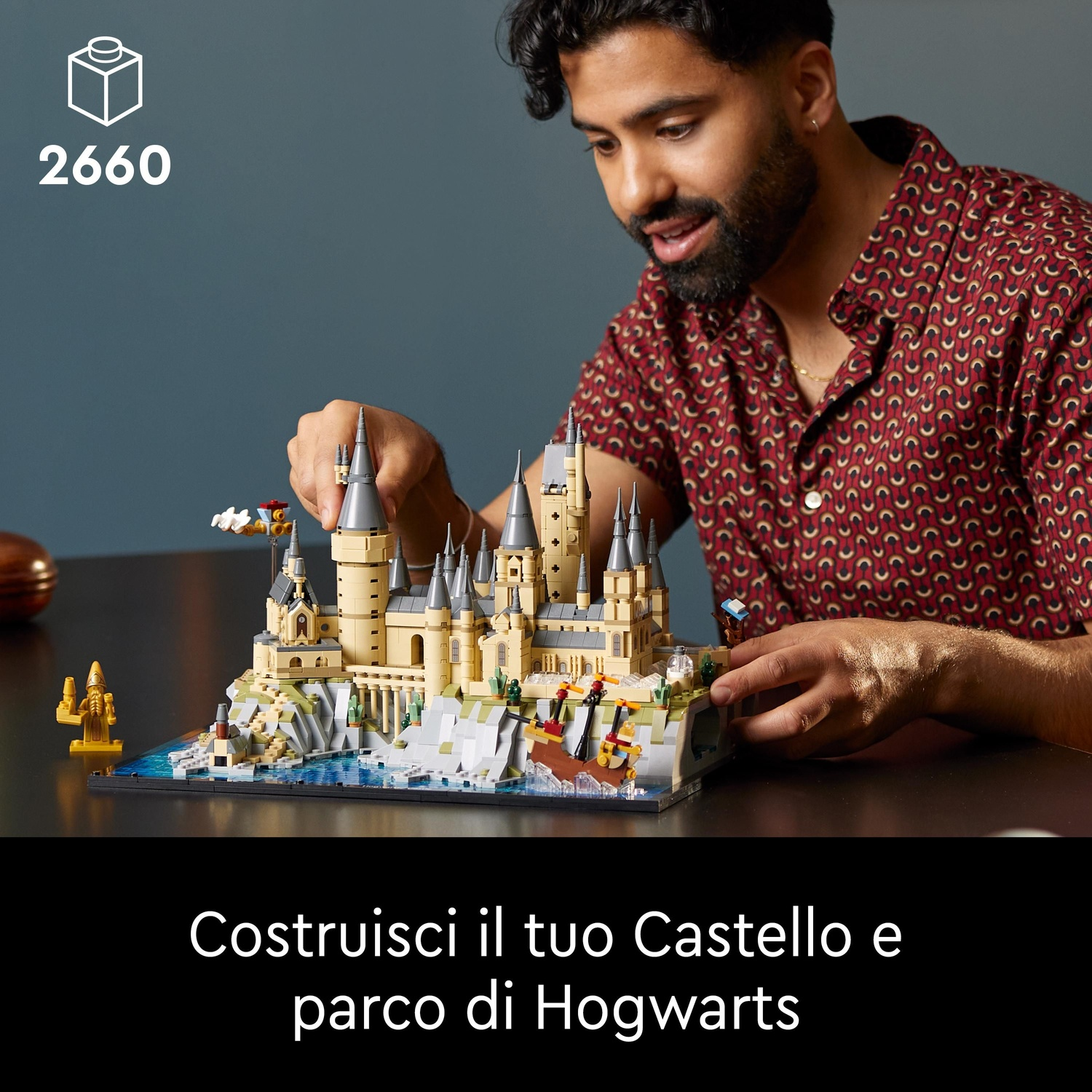 Uomo costruisce castello Lego di Hogwarts con torri e acqua.