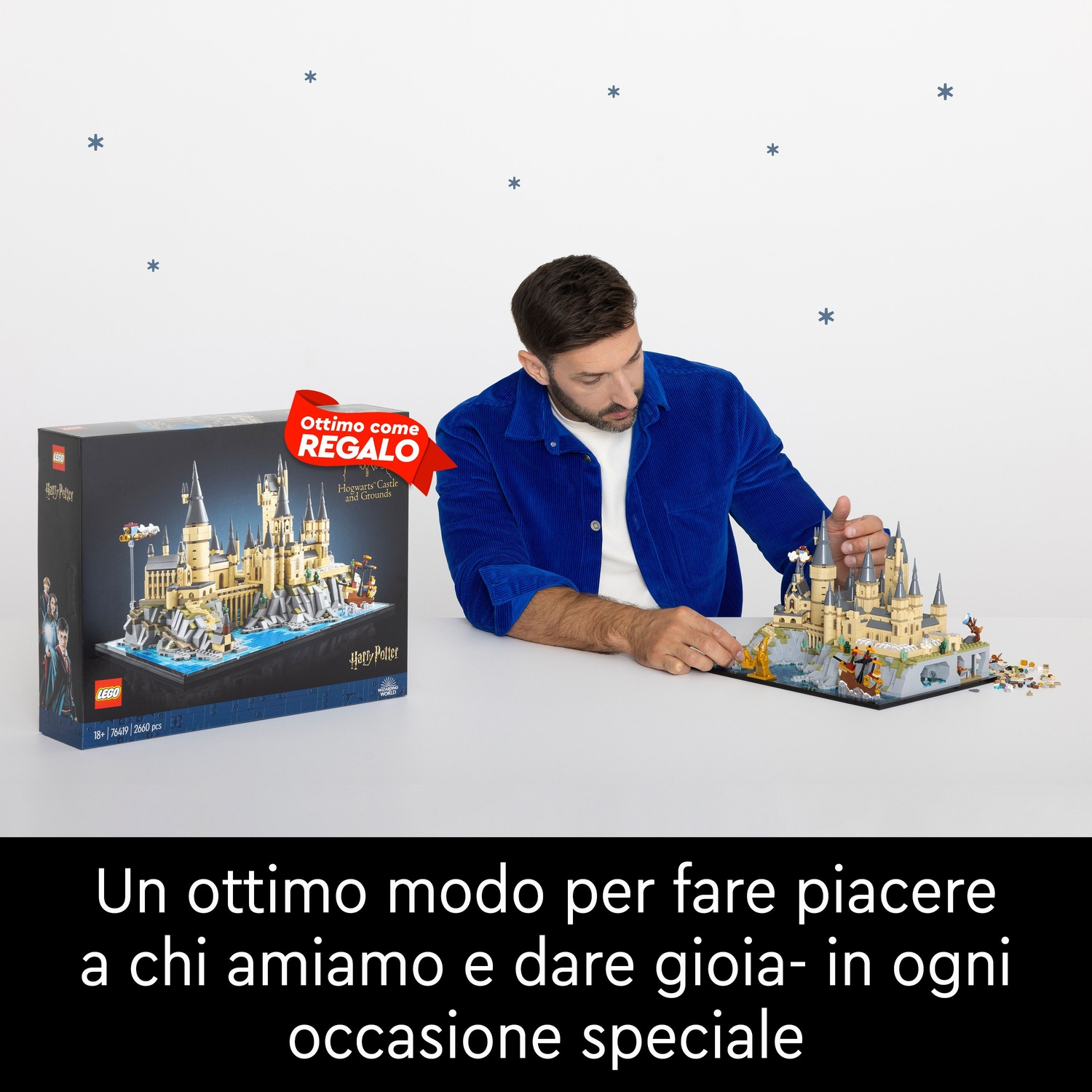 Uomo costruisce Lego Hogwarts. Scatola a sinistra, modello a destra. Muro bianco con stelle blu.