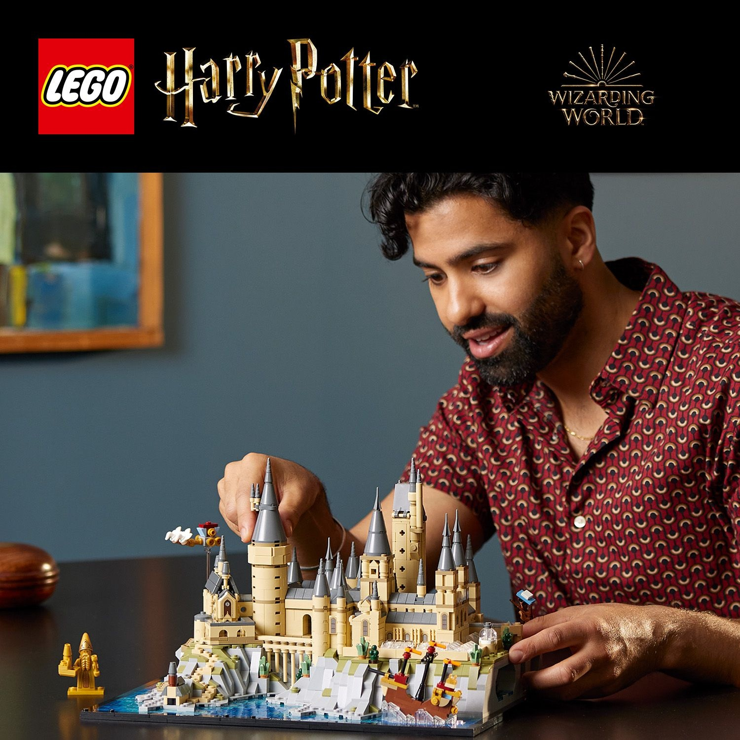 Un uomo costruisce un dettagliato modello Lego di Hogwarts, con torri e acqua.