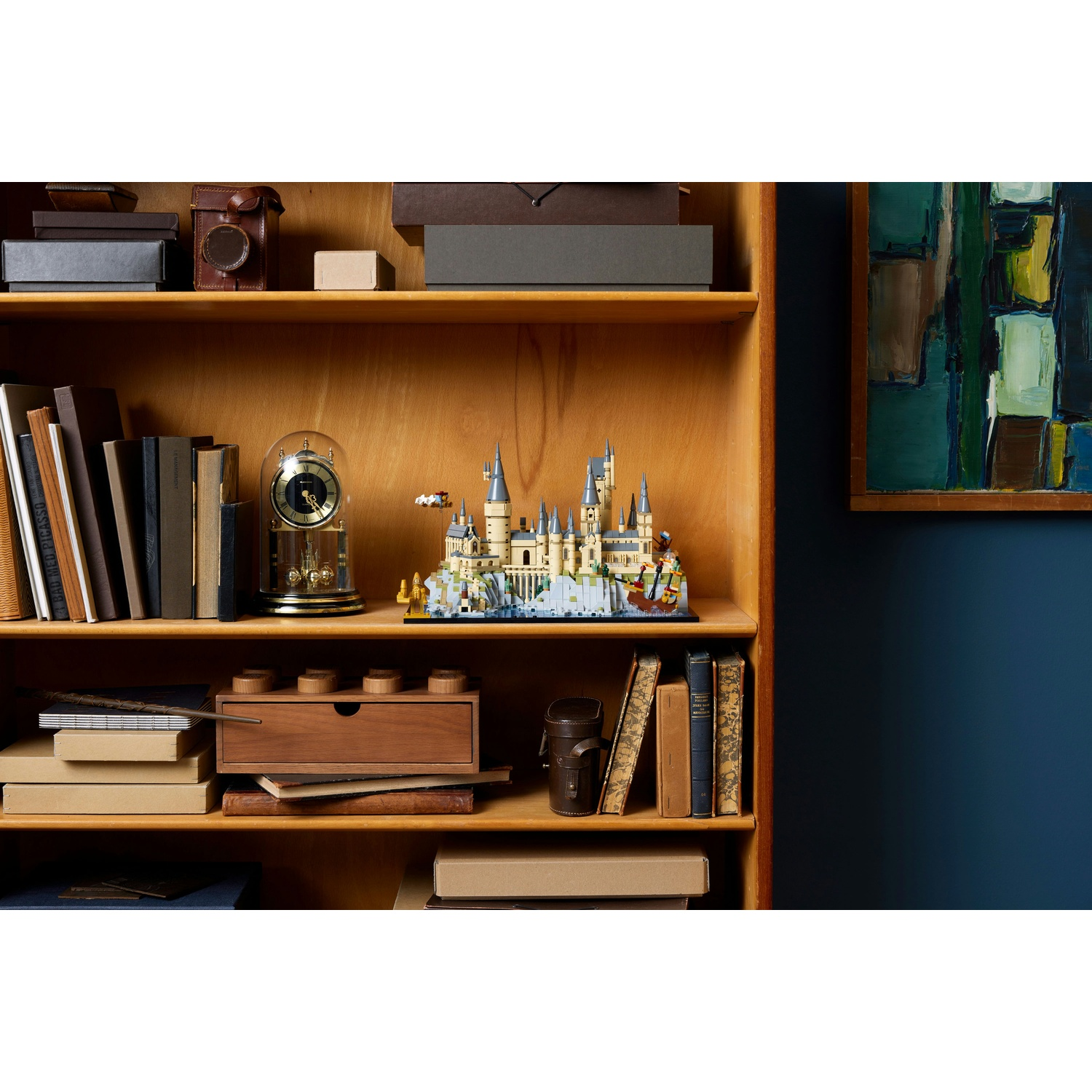 Un modello dettagliato di Hogwarts su uno scaffale con libri e decorazioni.