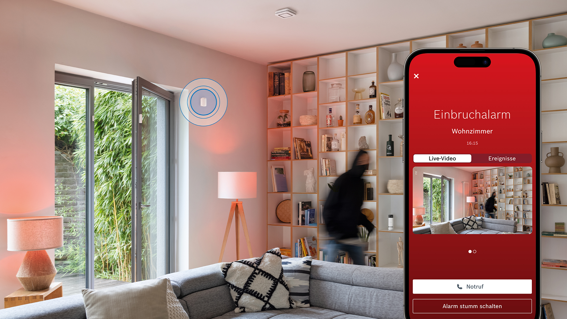 Einbrecher im Wohnzimmer, Überwachungs-App auf dem Handy zeigt Live-Video.