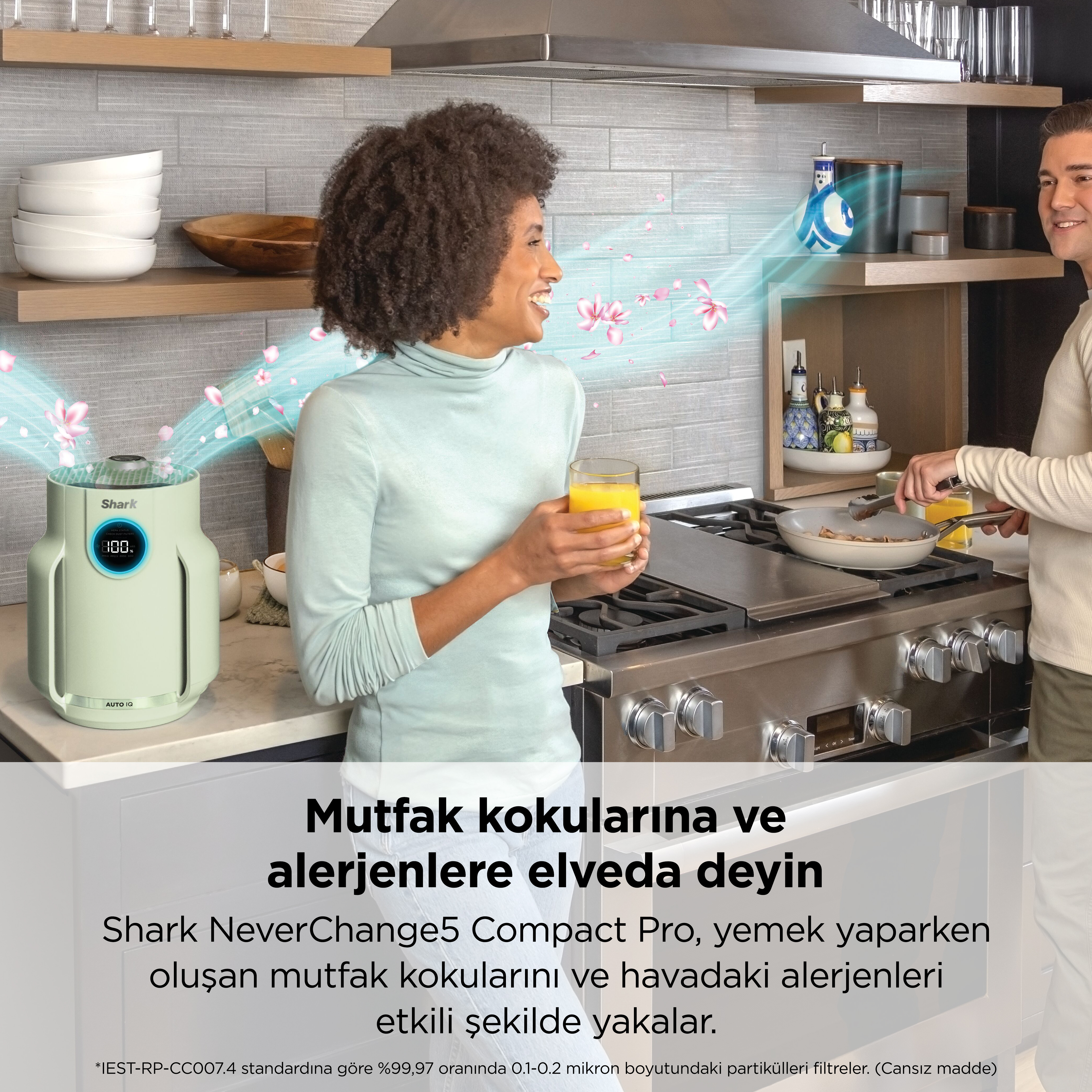 Mutfakta bir çift, solda hava temizleyici, uçuşan pembe çiçekler.
