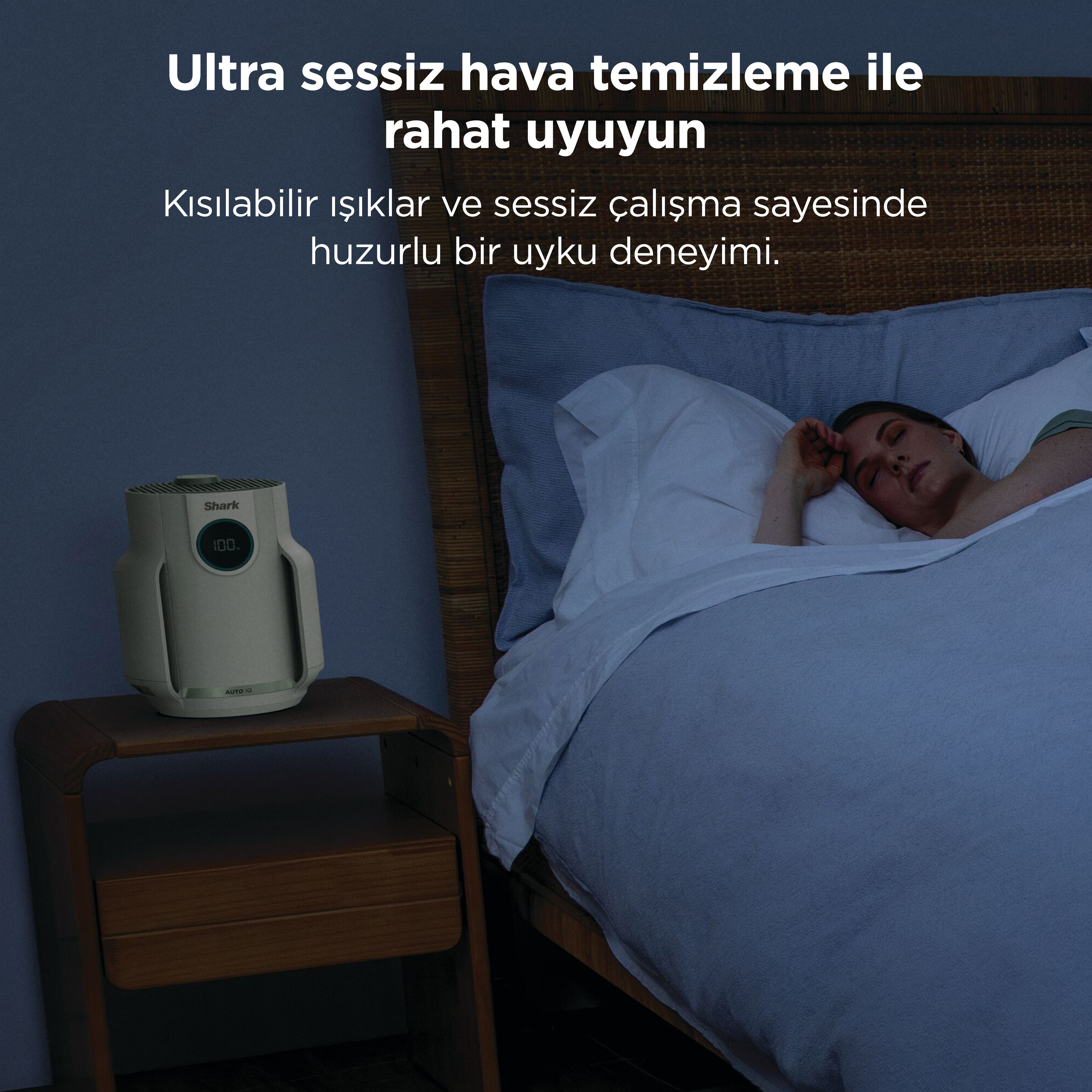 Bir kadın uyurken yatağın yanında bir hava temizleyici duruyor.