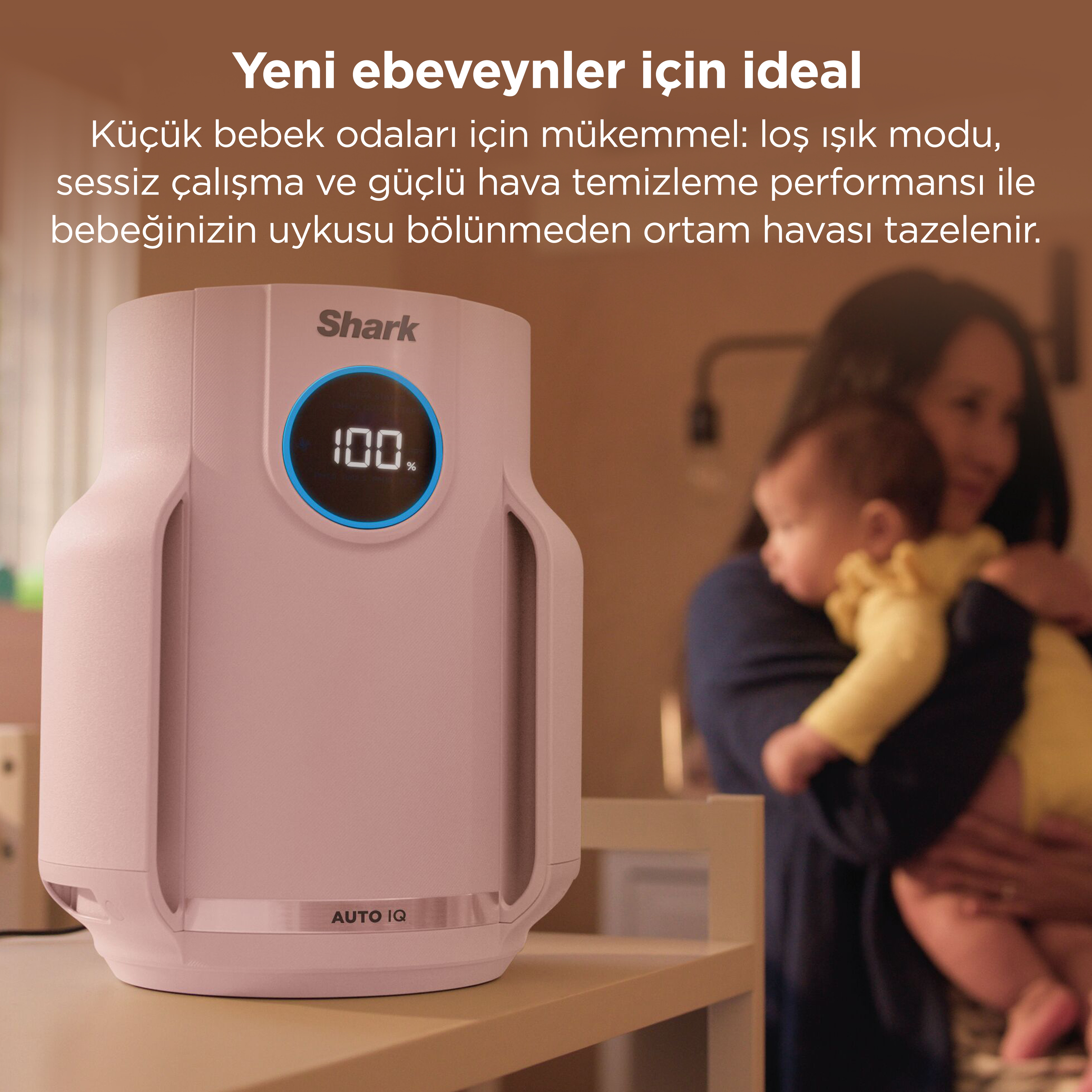 Shark logolu pembe hava temizleyici ve %100 göstergesi, bebeğini tutan bir annenin yanında.