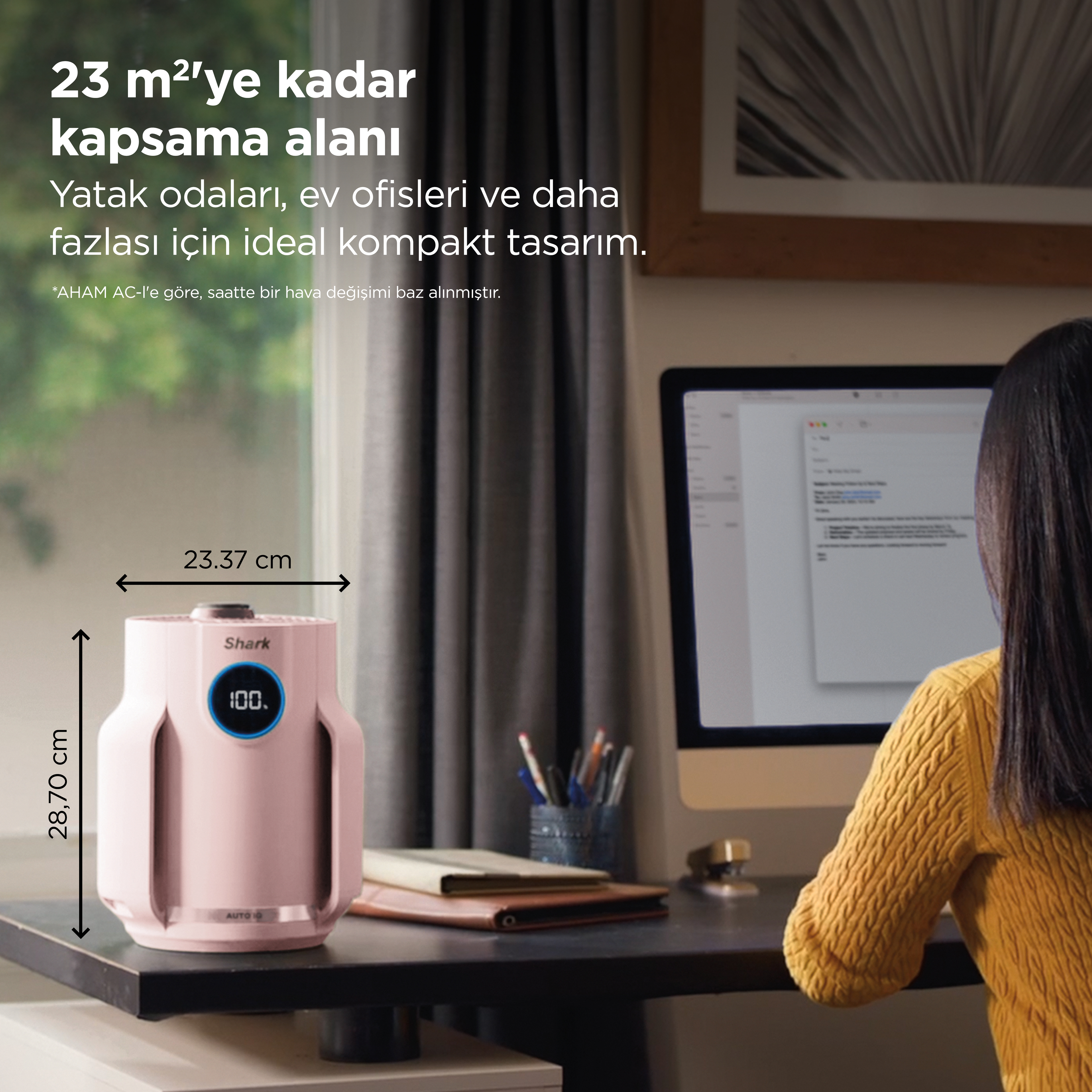 Mavi göstergeli pembe bir hava temizleyici, bilgisayarın yanında masada duruyor.