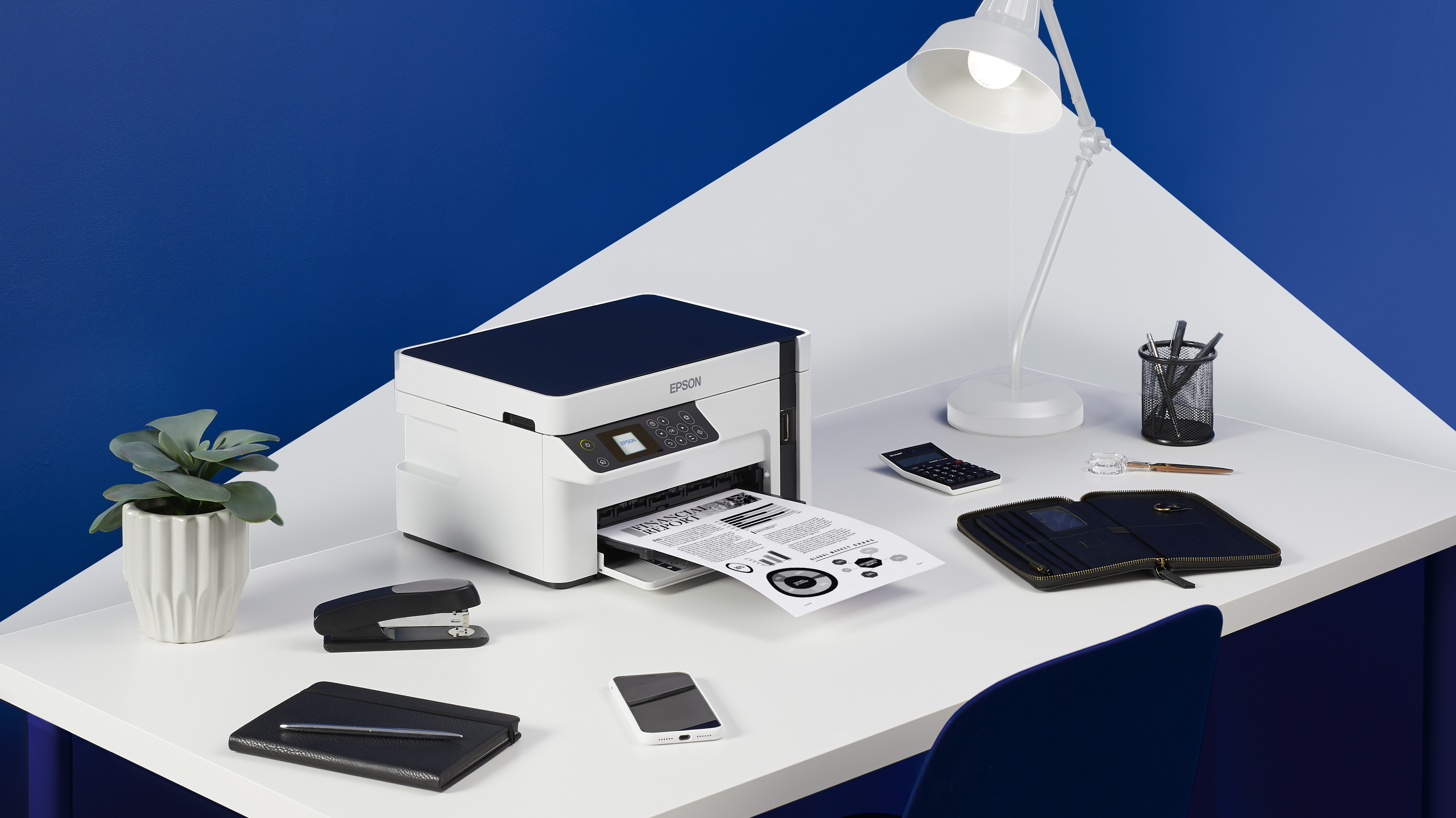 Ein weißer Epson-Drucker druckt einen Finanzbericht auf einem weißen Schreibtisch mit Büromaterial.