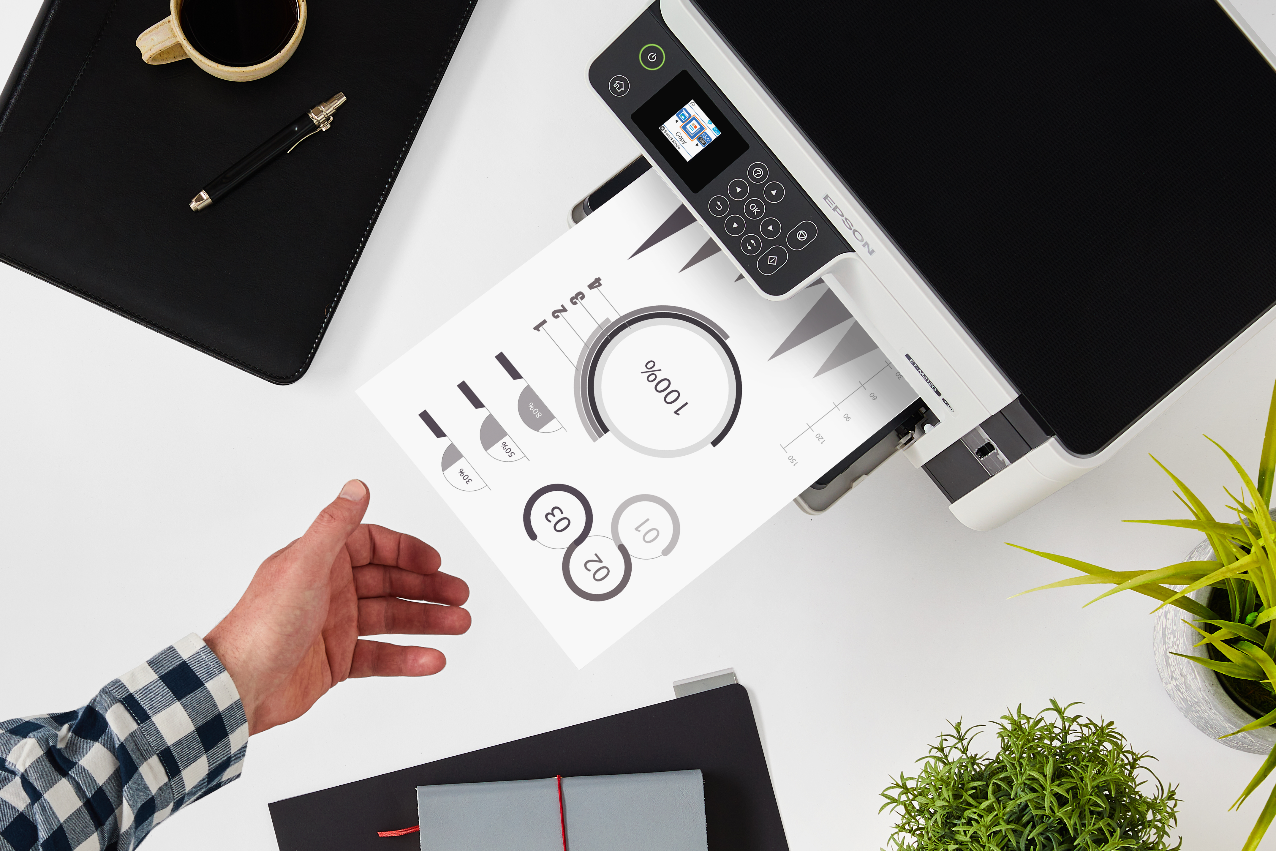 Ein Mann druckt ein Diagramm mit einem Epson-Drucker. Kaffeetasse und Stift liegen daneben.