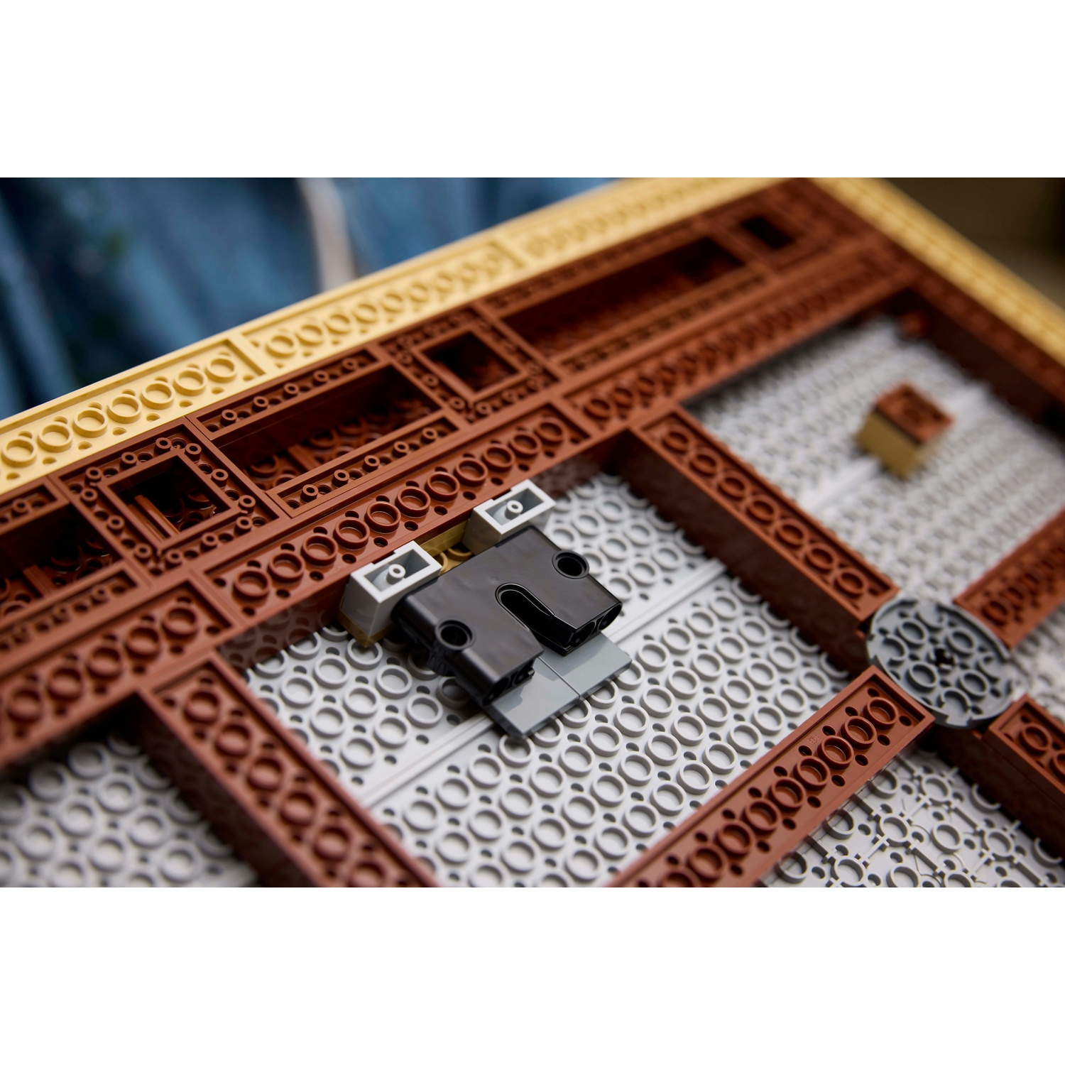 Primo piano di un pezzo Lego grigio scuro e nero su una base Lego grigia e marrone.