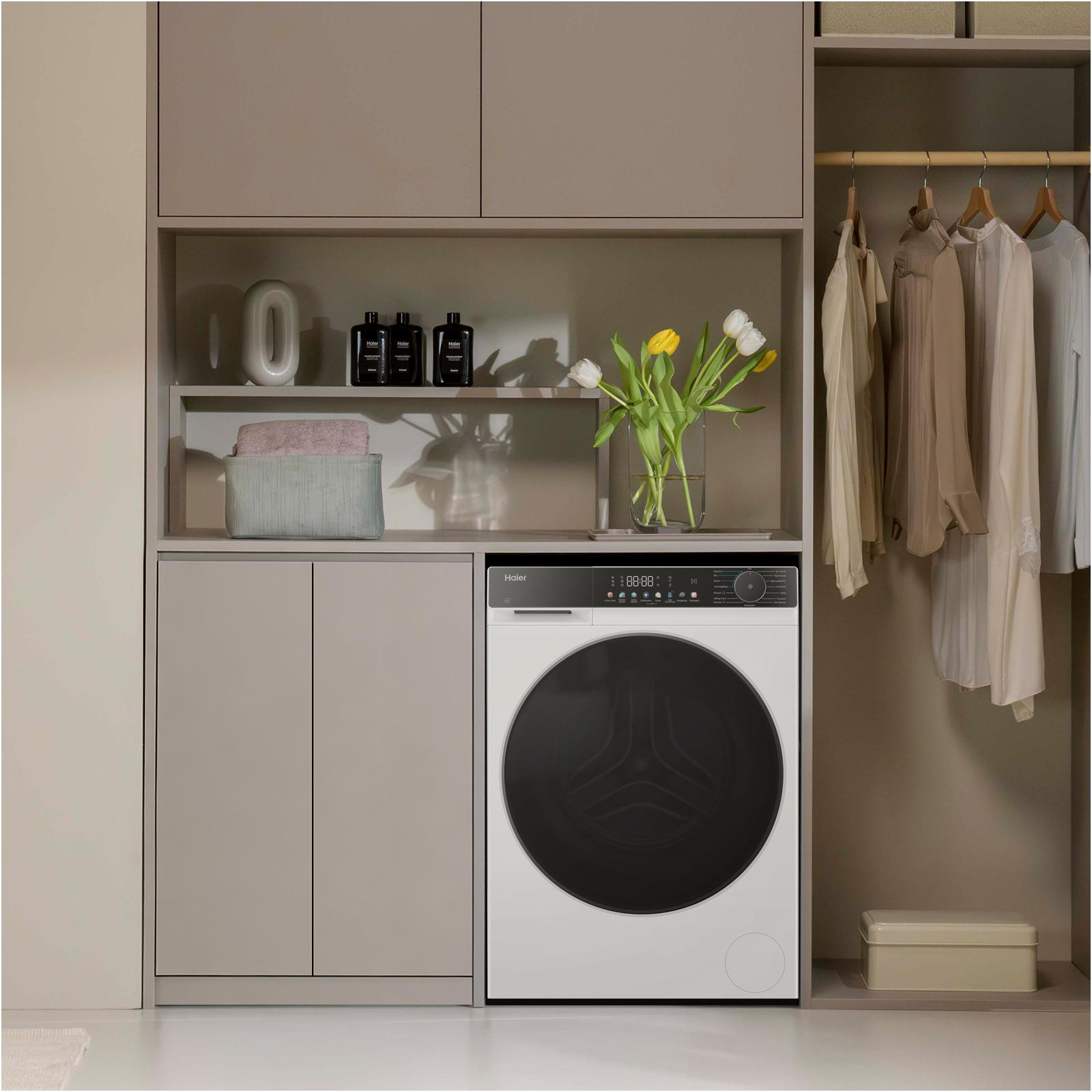 Eine Waschmaschine neben einem Schrank mit Kleidung, Blumen und Aufbewahrung.