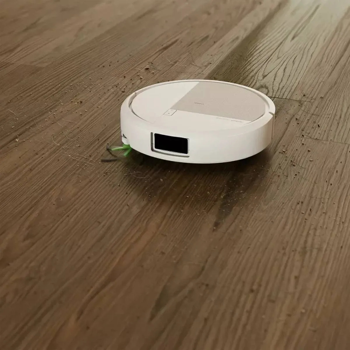 Biały robot sprzątający czyści drewnianą podłogę.